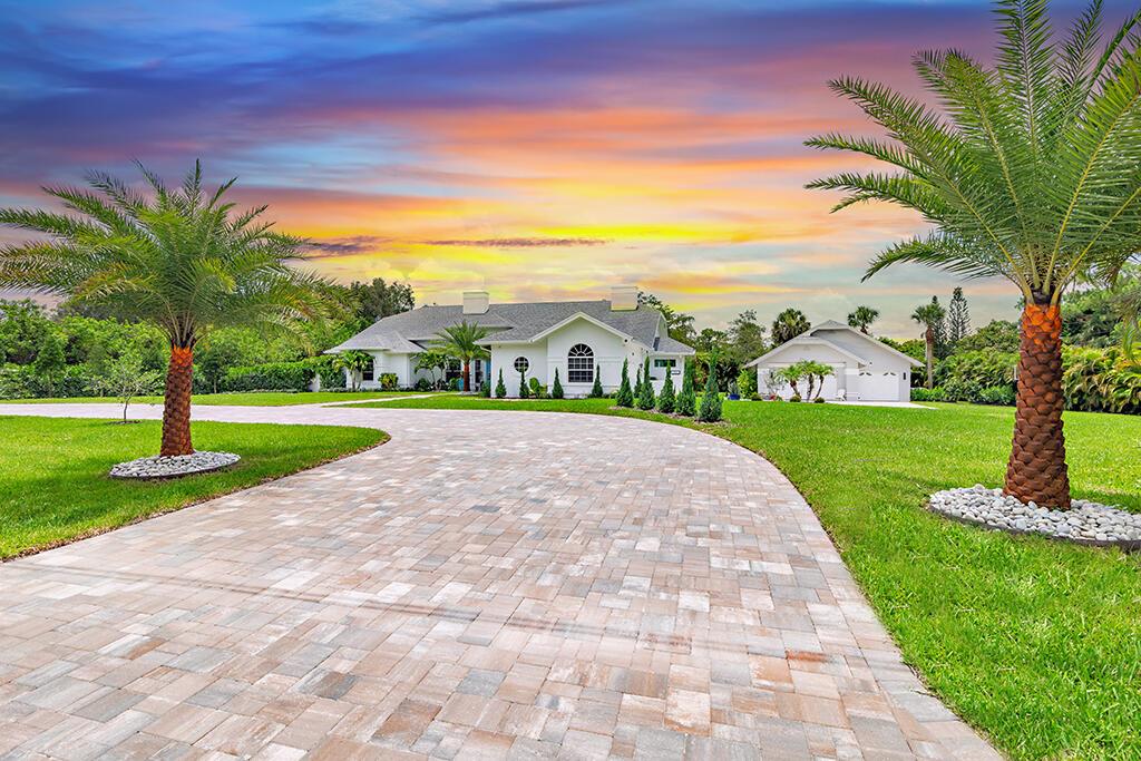 Discover the perfect blend of modern luxury and serene rural living in this newly remodeled custom home, nestled on 1.3 lushly landscaped acres in the highly sought-after Palm Beach Country Estates. Offering 4 bedrooms, 3 bathrooms, and over 3,254 sq ft of beautifully designed living space (5,733 total), this home provides privacy, comfort, and upscale features just minutes from top-rated schools, pristine beaches, shopping, and dining. The spacious circular paver driveway leads to a welcoming entrance, while the interior boasts expansive living areas ideal for both everyday life and entertaining. Soaring vaulted ceilings flood the open-concept layout with natural light, complemented by a thoughtfully designed split floor plan and refined finishes throughout. The primary suite is a