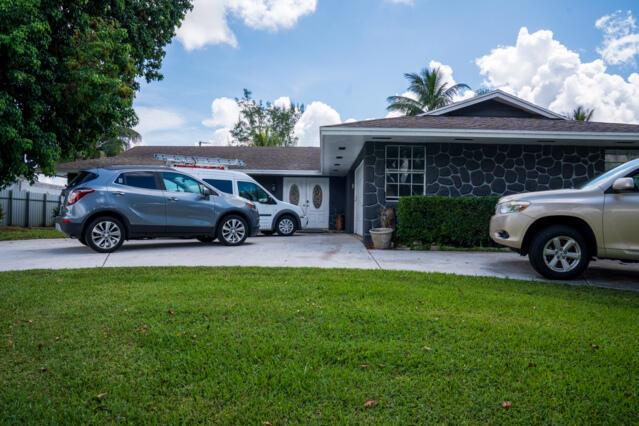 Gorgeous home on one of the largest lots in the community! This suburban oasis features a circular driveway, 2-car garage with work area, and inviting curb appeal with mature trees and a front-yard swing. The serene backyard offers a covered lanai (easily screened), large grassy area with room for a pool, and peaceful canal views. NO HOA--bring your boat or RV! This well-maintained property features an updated kitchen, tiled floors throughout, a versatile flex room The AC was replaced in 2013 and the roof is 2010. Home is on septic. Conveniently located near shopping, dining, beaches, parks, and the vibrant Downtown West Palm Beach, this home offers both comfort and convenience--perfect for family living and entertaining. Don't miss out!!!