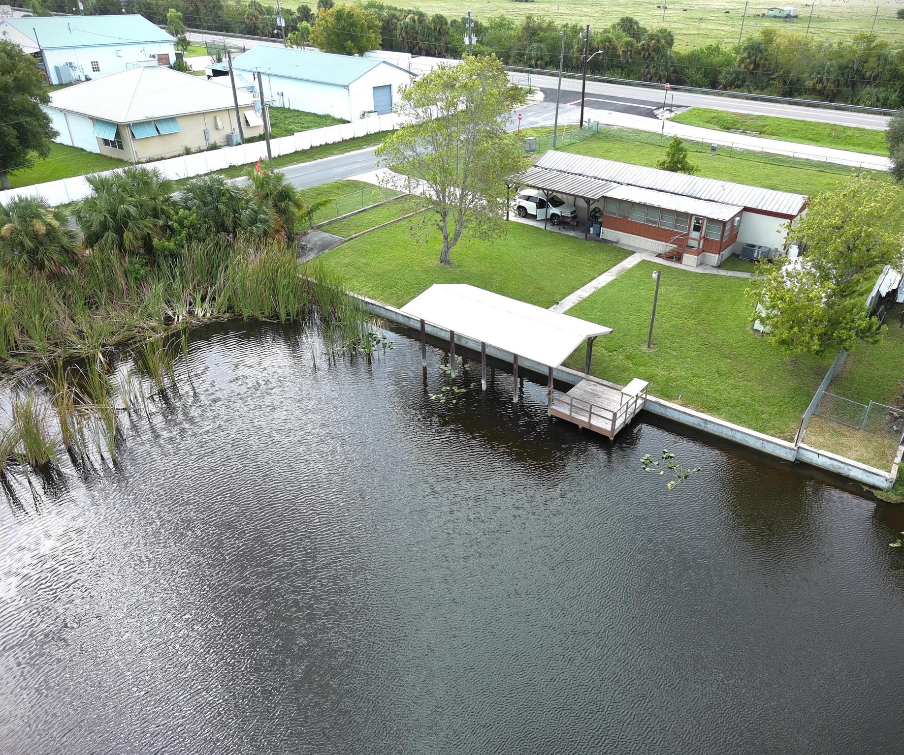 Sizable 113'x150' lot (.39 acres) on Lake O access canal. Zoned RES but can be C1 COMMERCIAL for highest and best use. Survey in hand. Prime investment location as infrastructure is increasing in Buckhead Ridge of Glades County (including new development of over 1,300 homes 1 mile to the West of BHR, and the proposed Bass Pro Resort & Marina 2 miles to the East of BHR). Location: Corner Lot 1 block from Gas station and 2 convenient stores. Property: 2017 seawall, 2021 Boat Ramp Roof, Chain Link Fencing, 2017 Carport, Gutters, Shed, Gas Range, Bar in Florida Room. Recent renovation to underside of home: Replacement and removal of polyethene plumbing; new insulation, vapor barrier & skirting. Prior damage from washer overflow disclosed in photos. Cash offers only.