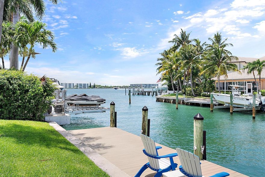 A BOATER'S PARADISE! A true gem in Palm Beach Isles, this rare waterfront home on Singer Island is just one lot from the point and offers beautiful views of the Intracoastal Waterway. This 4-bedroom, 3-bathroom home sits on an oversized 12,494 SF lot with 100 feet of prime water frontage. Tucked away on the cul-de-sac of prestigious Coral Way, residents enjoy exceptional privacy in this coveted enclave, accessed by the charming bridges at the community's entrance. The home has been tastefully renovated, featuring a tray ceiling in the great room that enhances the open-concept design, rich hardwood flooring, elegant bathrooms, and crown molding throughout. Boating enthusiasts will appreciate the 40,000 lb. lift, additional 2,500 lb. lift, and a large 66' x 8' deep-water dock accommodates