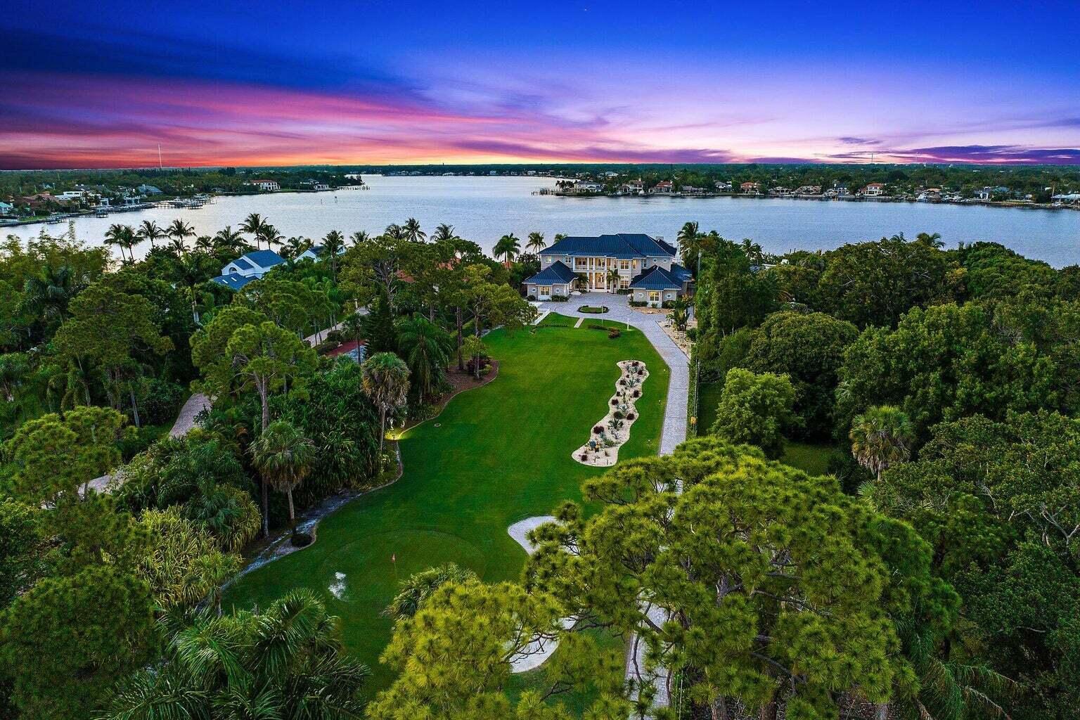 Introducing 5874 Pennock Point Rd., offered for the first time in over 30 years! Built in 2020, luxury living meets unparalleled leisure. Nestled on a sprawling riverfront site with almost 2 acres of lush tropical landscaping, this awe-inspiring estate home boasts 5 bedrooms, 6 full & 2 half bathrooms, and a unique par 3 in the front yard with a second-story tee box, offering a golfer's paradise right at your doorstep. Upon entering the grand foyer, prepare to be captivated by the seamless blend of sophisticated design and top-of-the-line finishes. Built for both work and play, this stunning property includes two dedicated office spaces, perfect for the modern professional. Highlighting its waterfront location, this home is one of very few on the Loxahatchee River to have