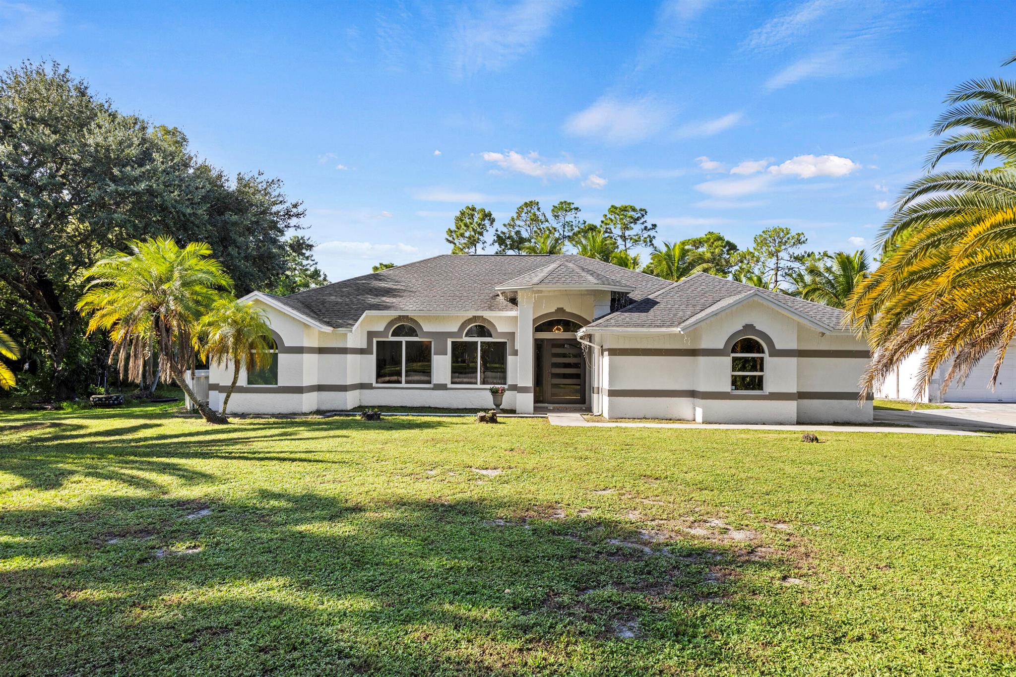 Well maintained 3 bedroom, 2 bathroom, Pool home located on 1.14 acres in the heart of Loxahatchee, only minutes from Westlake, Avnir, gas stations, and shopping centers. The property features an attached 2 car garage + a 900 sq ft detached 4 car garage, impact rated doors and windows, newer roof, newly renovated kitchen that opens to bring living spaces, cathedral ceilings, screened pool and back porch, extended driveway, and paved road. The property also includes a separate shed, a serene pond, and ample room for gardening and/or raising animals, including horses. With NO HOA restrictions, you'll enjoy the freedom to bring your boat, truck, trailer or RV. The detached garage can be turned into a workshop area or possibly a guest house. This property offers the perfect blend of
