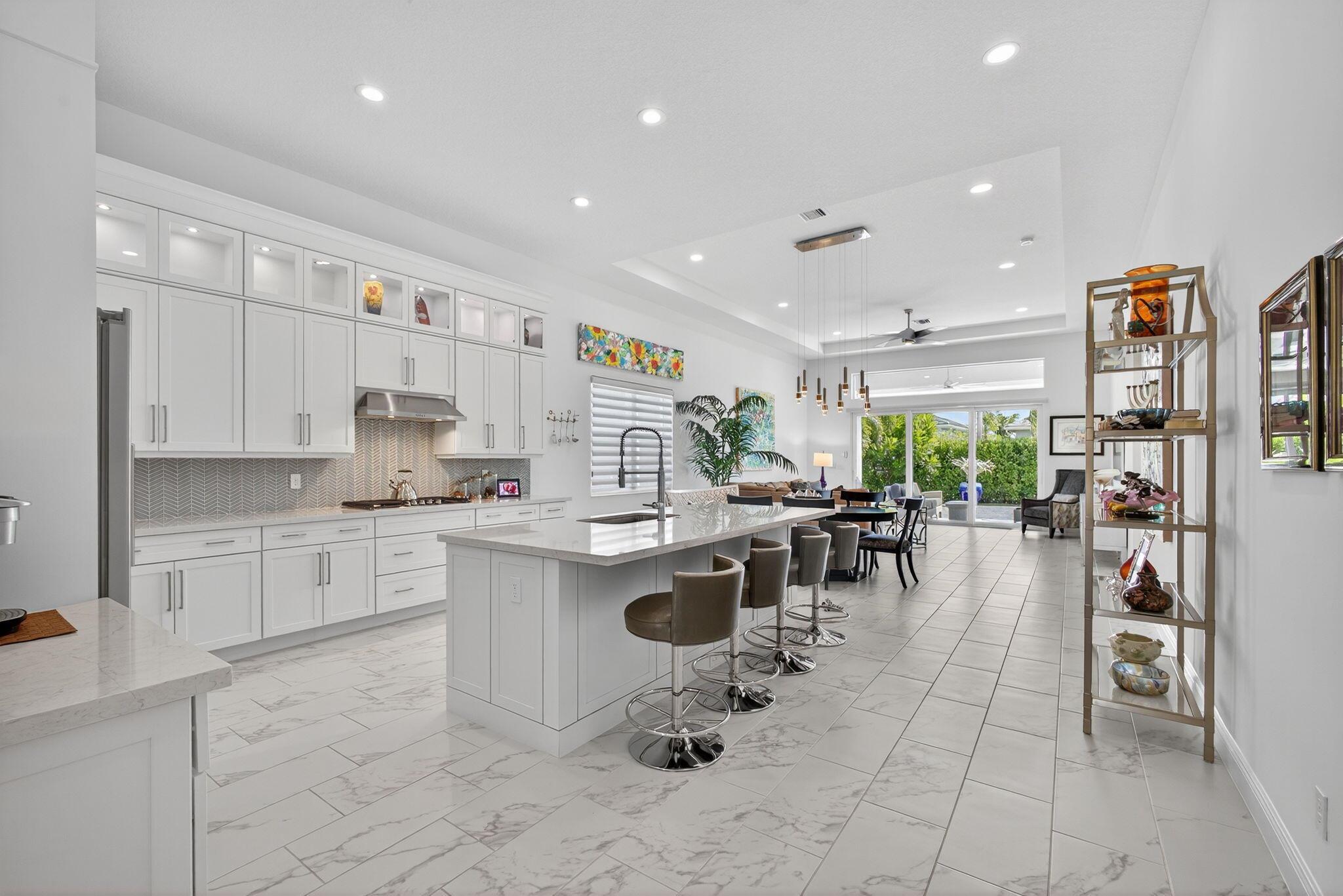 Welcome to the extended McKenna, a beautifully designed Coastal home that captures the relaxed elegance of Florida living. The stone-accented exterior and bright, open floor plan set a welcoming tone from the moment you arrive. Inside, the expanded gourmet kitchen is both stylish and functional, featuring quartz countertops, a larger island, a walk-in pantry, and an added row of lighted glass-front cabinets. Designer lighting, Minka Aire ceiling fans, and upgraded recessed fixtures throughout the home create a soft, inviting atmosphere. Custom touches continue with Closets by Design organization systems in the pantry, primary suite, and storage areas, along with a Toto bidet in the primary bath and Hunter Douglas Pirouette window treatments, many with remote controls for effortless