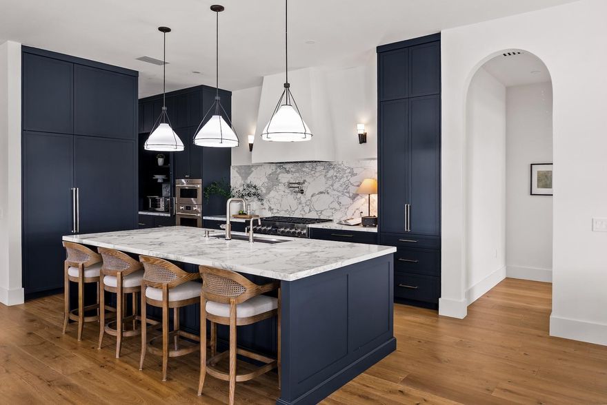 Step into a residence where every detail has been thoughtfully curated to balance modern functionality with timeless design. At its heart lies a bespoke kitchen, enveloped in Italian Statuario Belgia marble with a striking three-foot backsplash, complemented by a Sub-Zero/Wolf appliance suite, handcrafted custom cabinetry, and European white oak hardwood floors that flow seamlessly throughout the home.
The primary suite offers a serene retreat, complete with travertine floors, custom dolomite vanities, walk-in rainfall shower elegantly enclosed by a tailored single pane of low-iron glass, and a two-person soaking tub reminiscent of a luxury spa experience. Outside, enjoy panoramic lake views, a fully fenced yard, and the privacy of a generous one-third-acre homesite.