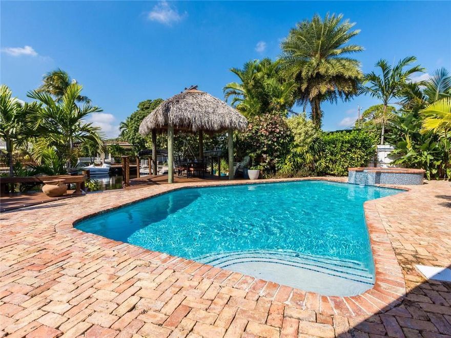 Beautifully renovated 4/3 mid-century waterfront pool home in a prime location! Offered unfurnished, this sprawling ranch has it all—over 3,100+ square feet of living space. The split bedroom plan features two primary suites with ensuites, plus two additional guest bedrooms. The home exudes charm from the moment you enter through the gated front courtyard. A formal foyer opens to a spectacular great room showcasing a stylish modern kitchen with waterfall countertops, breakfast bar, and newer appliances. Additional highlights include formal dining, an eat-in kitchen, and a light-filled living room surrounded by windows on three sides overlooking the heated pool and spa. Enjoy outdoor living with a covered patio, 60 feet of waterfront, a thatched-roof tiki hut, and a two-tiered dock. All complemented by a Chicago brick paver patio. Laundry room, large pantry, and attached two-car garage complete the home.