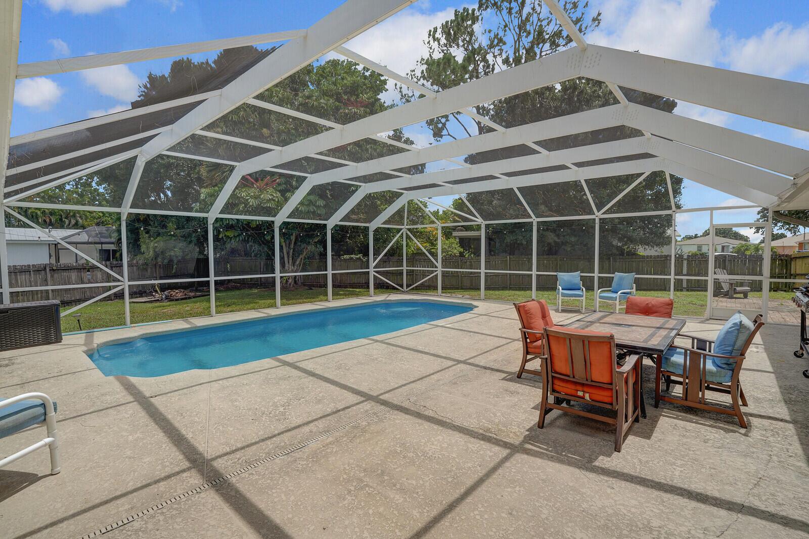 Welcome to this true Port St. Lucie gem with nearly 2,000 square feet of living space. Perfectly situated on an oversized fenced corner lot, this residence offers the ideal blend of modern comfort and Florida living. Step inside to a bright and spacious split floor plan that is versatile to fit every buyer's needs. The owner's suite has an expansive sitting area that looks out onto your private, screened-in pool. This backyard paradise is perfect for cooling off on a hot day or entertaining guests year-round. The kitchen, with granite counters and stainless steel appliances, overlooks the large family room which features surround sound and ceiling speakers. You can move in with complete peace of mind, knowing all major systems are new. The roof, water heater, and A/C were replaced in 2024