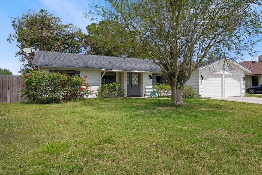 Welcome to this beautifully updated 3-bedroom, 2.5-bath, 2-car garage home, offering charm, space, and a prime location. Freshly painted white walls and rich wood-look ceramic tile flooring flow seamlessly throughout the open layout. The spacious living room is filled with natural light from large windows and accented by built-in shelving and updated ceiling fans. The kitchen features white cabinets, brushed nickel hardware, warm earth-tone tile countertops, a large island with a cooktop, double ovens, and a stainless steel refrigerator. French doors lead to a screened-in covered patio, perfect for entertaining. The primary suite includes a remodeled bathroom with a walk-in shower featuring marble-style tile and flooring. Secondary bedrooms are bright and inviting, sharing a full bathroom with a white vanity and tiled shower-tub combo. The oversized laundry room offers extensive shelving, and the attached 2-car garage includes additional comfort with a window A/C unit. Enjoy the private, fenced backyard with mature landscaping, a fire pit, and plenty of room to relax or entertain. Conveniently located near schools, parks, shopping, and dining, this move-in ready home is waiting for you!