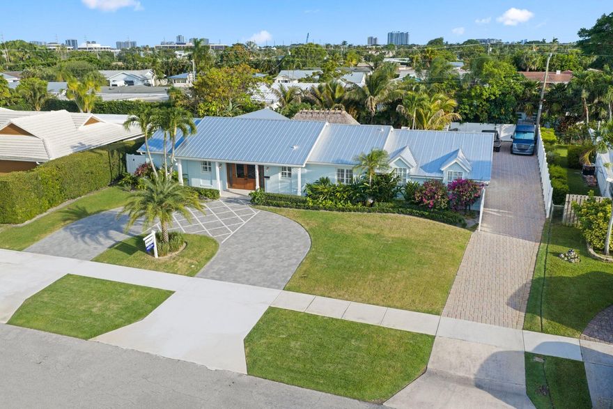 Nestled in the heart of North Palm Beach's Country Club section, this beautifully upgraded home sits on an oversized 13,000 sq. ft. lots. Designed for easy indoor-outdoor living, the home offers a private backyard that feels like a tropical retreat, with mature palms, blooming orchids, expansive turf space, and a large tiki hut with outdoor Sonos speakers. This 3 bedroom 2 bath home features large living spaces, formal dining room and a huge kitchen and wet bar perfect for entertaining. This home is very light and bright with sliders and windows throughout. Spacious bedrooms with walk-in closets and fully updated bathrooms. The interior features include natural stone countertops, wood look porcelain floors and custom wall coverings. The bedrooms, kitchen and living room have custom plantation shutters and the master bedroom has automated Hunter Douglas black out shades. This home underwent a complete interior remodel in 2021 and has been extensively upgraded since, with no expense spared. Major improvements include a metal roof (2020), new pool (2020) and travertine deck, full impact glass, brand-new front doors and sliders (2025), full-home water filtration, updated plumbing with PVC all the way to the street (2021), newer AC (2022), redone attic ductwork (2026) Icynene attic insulation (2025), newer hot water heaters (2024 and 2026), updated pool equipment (2025), new turf (2026), circular front drive, irrigation, Bermuda grass, landscaping (2025), and landscape lighting (2026.)  An electric gate provides private rear access, and the property also includes complete plans and drawings for an addition that would make the home a 5-bedroom, 4-bath residence with a large laundry room, ready to be submitted for permits.  The permited and enclosed garage space is currently unfinished and offers exceptional flexibility for a buyer's vision. Restore it to a traditional garage, create additional living space, or take advantage of the seller's existing plans for a future home addition. The home also has a full security and camera system installed. This is a rare opportunity to customize and expand to suit your lifestyle and purchase a truly turnkey home in North Palm Beach at an approachable price, on one of the best streets in the neighborhood.