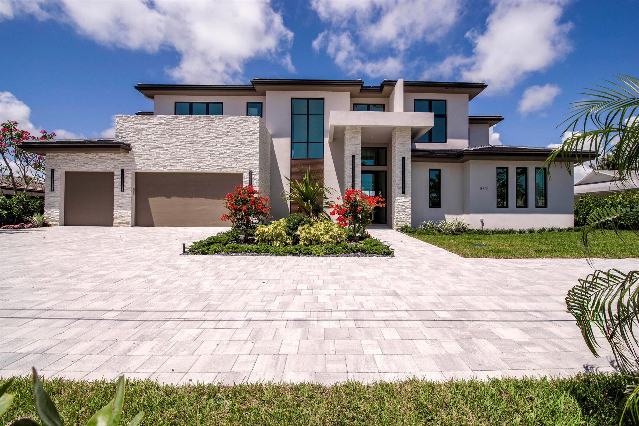 Balancing modern elegance with a true waterfront lifestyle, this brand-new construction by Dell Development is a standout offering in the prestigious boating community of Paradise Port, located in the heart of Palm Beach Gardens. This exceptional 4,920-square-foot estate boasts 95 feet of waterfrontage with a brand-new seawall and delivers refined luxury in a thoughtfully designed two-story layout. Featuring 5 bedrooms and 6 bathrooms, the home seamlessly blends sophisticated design with functional comfort. From the moment you enter, clean architectural lines and a light-filled open layout make a lasting impression. The main living area showcases neutral-toned large-format tile, a sleek stone-surround fireplace, and expansive 10-foot floor-to-ceiling sliders that blur the line