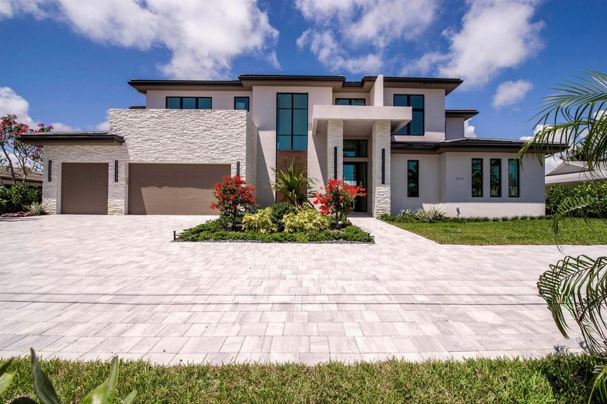 Balancing modern elegance with a true waterfront lifestyle, this brand-new construction by Dell Development is a standout offering in the prestigious boating community of Paradise Port, located in the heart of Palm Beach Gardens. This exceptional 4,920-square-foot estate boasts 95 feet of waterfrontage with a brand-new seawall and delivers refined luxury in a thoughtfully designed two-story layout. Featuring 5 bedrooms and 6 bathrooms, the home seamlessly blends sophisticated design with functional comfort. From the moment you enter, clean architectural lines and a light-filled open layout make a lasting impression. The main living area showcases neutral-toned large-format tile, a sleek stone-surround fireplace, and expansive 10-foot floor-to-ceiling sliders that blur the line