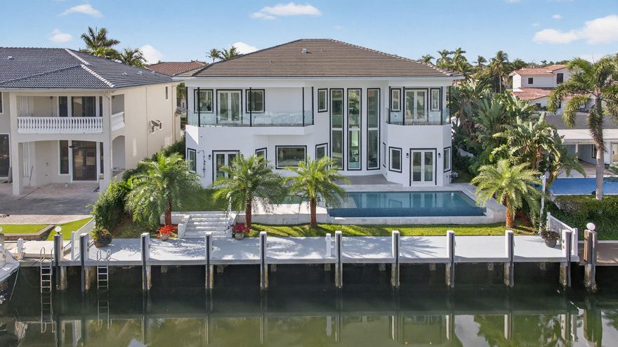 Your Waterfront Sanctuary Awaits. Discover this stunning, newly constructed contemporary home in prestigious Lighthouse Point. This exceptional estate features an 80-foot dock equipped with water & electricity hookups, perfectly positioned on a canal deep enough for a sailboat, offering unrestricted ocean access with no fixed bridges. The home showcases a spacious open-concept layout with 14-foot ceilings and a gourmet kitchen finished with high-end appliances, two wine fridges, under-counter and in-cabinet lighting—making every gathering an event to remember.The new owner also has the opportunity to select their own drawer and cabinet pulls.  There are two primary suites. The first-floor suite features French doors to the patio and pool, costume closets, and a spacious walk-in shower with a rainfall shower feature. A larger primary suite on the second floor features French doors leading to the balcony with glass railing overlooking the Intracoastal. The primary suite bathroom includes a soaking tub, separate vanity areas, and an oversized dual shower with a rainfall shower feature. The two costume closets provide ample space for all your belongings.  Modern conveniences abound, including an elevator-ready layout, four A/C units, and two water heaters for maximum efficiency, as well as two laundry rooms and a three-car garage with electric vehicle charging capabilities. The balconies are equipped with sleek glass railings, and the second-floor laundry room includes a sink for added convenience. A heated saltwater infinity pool and hot tub complete your private outdoor oasis. Set on an 8,000-square-foot lot, this residence offers total freedom with no HOA fees.