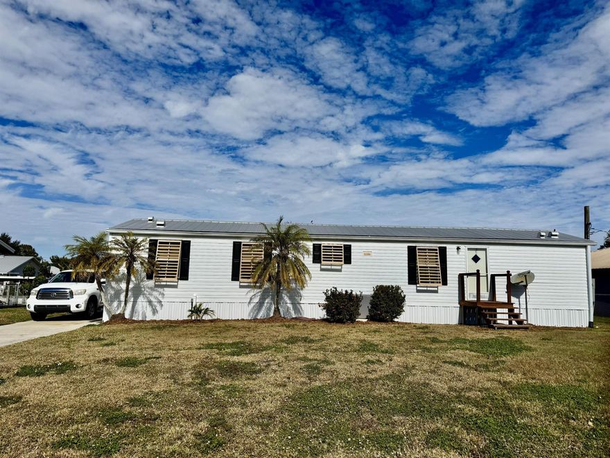 TAYLOR CREEK ISLES~ LAKE ''O'' Access.  Delightful 2005 SWMH. 2 Bd/2 Ba, 12x29 screened back porch. Split floor plan. Bright and cheery and full of charm. Metal roof, Bimini Shutters. 10x16 and 11x11 storage sheds. Concrete seawall. Driveway is long enough for boats and cars - even a RV! Fully furnished and ready to be your FLORIDA GET-A-WAY! Dimensions are approximate, must measure for exact