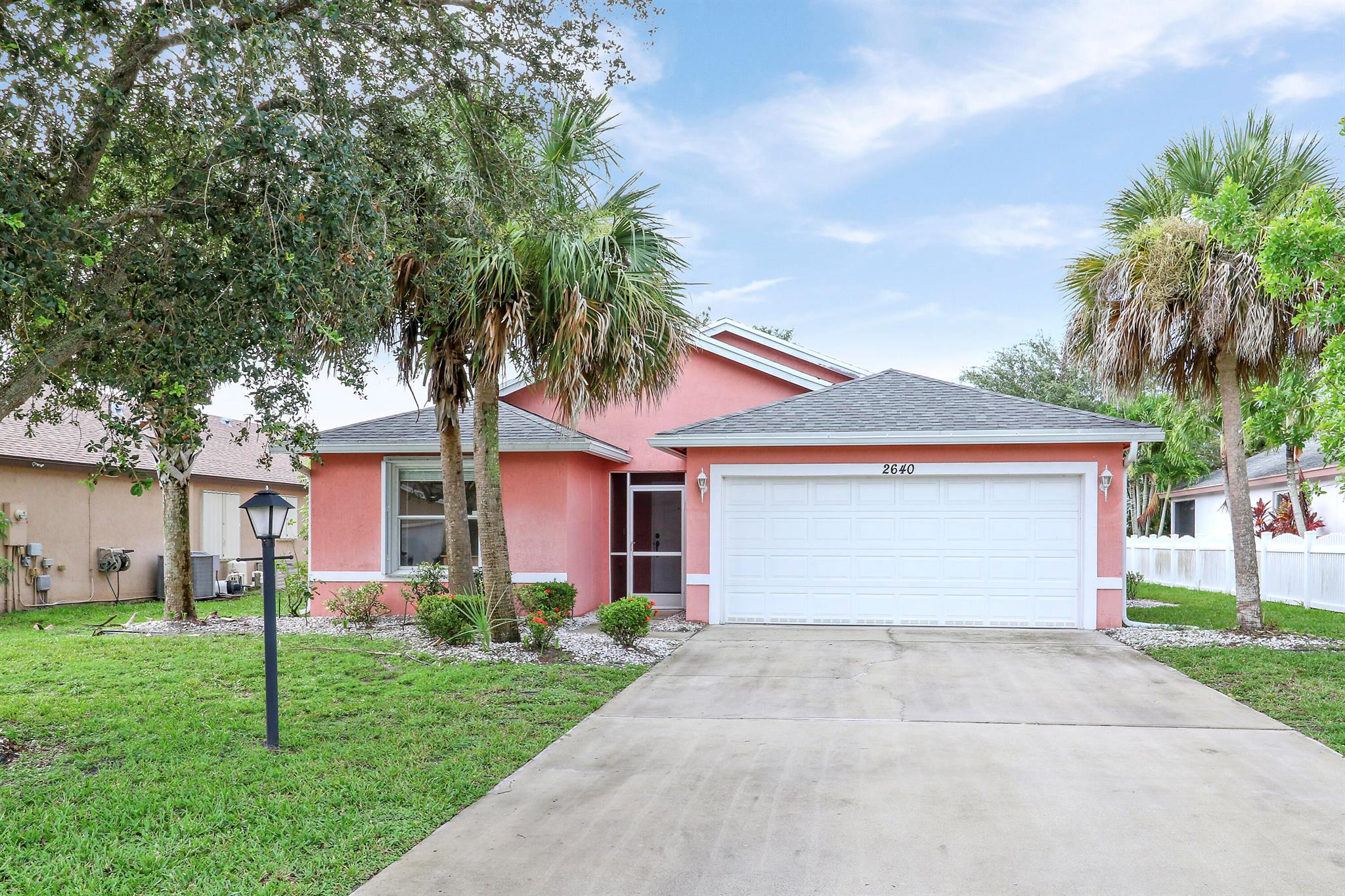 Welcome to this charming and well-maintained 3 bedroom, 2 bathroom, 2-car garage home located in the desirable St. Lucie Falls 55+ community. This inviting home features a split floor plan, vaulted ceilings, generous living and dining spaces. The large kitchen offers beautiful white cabinets, an eat-in-area breakfast nook, and a breakfast bar, making it functional and ideal for entertaining and family gatherings! The primary bedroom suite includes his and hers walk-in closets, an en-suite bathroom with a garden tub, a walk-in shower, plus separate sinks, vanities, and a makeup station. Step outside to your screened-in patio, great for morning coffee or relaxing with a cool beverage. BRAND NEW A/C. Resort-style amenities include two sparkling in-ground pools, two clubhouses, tennis, pick