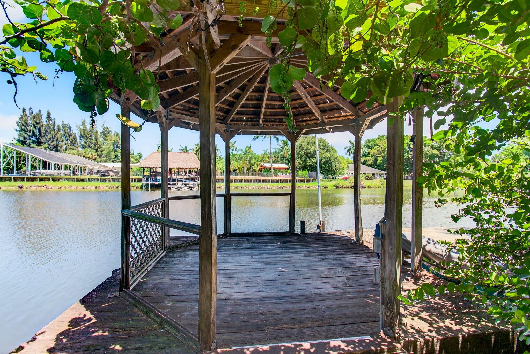 BEYOND THE GATE Lies Your Private Caribbean Paradise. Tucked away on 1/2 + of an acre, this secluded retreat is hidden behind its own motorized gate, revealing a lush tropical oasis brimming with native, indigenous plants and numerous citrus trees including yuzu, calamondin, and a variety of limes. The atmosphere transports you straight to the Caribbean, yet the best part is its location on a navigable waterway, offering direct access to the CHAIN OF LAKES. Spend your days kayaking from your private launch, boating from your dock, water skiing, fishing, or simply soaking in the beauty of nature from your Gazebo. There's nothing quite like the convenience and adventure of living on the water.