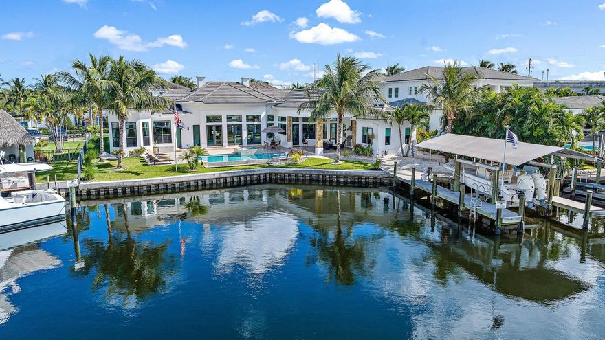 Welcome to this waterfront oasis with over 120 ft of deep water frontage, just one canal from the Intracoastal waterway. Built in 2017, this British West Indies Style home features 4 bedrooms & 4 baths, including a guest home. Step inside where you will be greeted by your majestic great room boasting 16' ft ceilings & sprawling waterfront views.  Just one minute to the intracoastal, this home is a boater's dream featuring a 14k lb covered boat lift & 2 docks. The location & shape of this 1/3 acre lot is at the widest part of the canal, allowing for a better turning radius & more water frontage making it a premium lot in the community! This home was custom built with only the finest of craftsmanship & attention to detail at every turn. Stunning chef's kitchen features a spacious island w/ 3" quartz waterfall edge, high-end appliances, & sleek custom cabinets w/ inlaid TV to create a bold statement in this fabulous kitchen.

This home is designed for entertaining, featuring a saltwater pool & spa, & travertine tile sun deck overlooking the waterway. The outdoor kitchen is equipped w/ TV, hooded vent, ice maker, & phantom screens on the covered lanai. 

The meticulous attention to detail extends to the interior w/ a custom frameless wine display & custom solid doors & trim,  Restoration Hardware light fixtures & hardware, surround sound & rectified wood-look tile throughout. The primary suite offers a private office w/ bay windows. A guest house w/ stunning waterway views comes complete w/ a full bathroom & refrigerator.. Whether enjoying the tranquility of the water or entertaining in your palatial living room, this property is designed for those who appreciate the finer things in life.