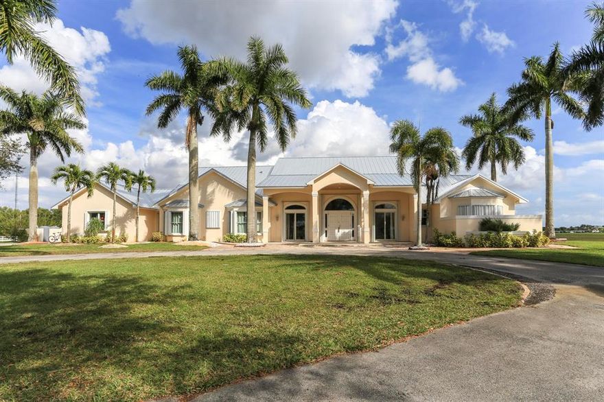 Prime location & never been on the market estate in Palm Beach Point! One of the largest lots in the community, this 6.4 acre property is both quiet and private, overlooking lush landscaping & polo fields.Custom built home w/ 5 bedrooms & 5 full bathrooms, massive screened and covered patio, full accordion shutters throughout & 3-car garage, & plenty of space to build the elements of your desires. The home boasts custom woodwork throughout- no detail was spared in the craftsmanship of this home. As you enter the foyer, you'll be greeted with beautiful marble floors & cathedral wood ceilings. The master bedroom includes two walk-in closets plus a bonus room. The gorgeous metal roof is less than 2 years old, the home's two water heaters are new & there is a whole-home reverse Osmosis system
