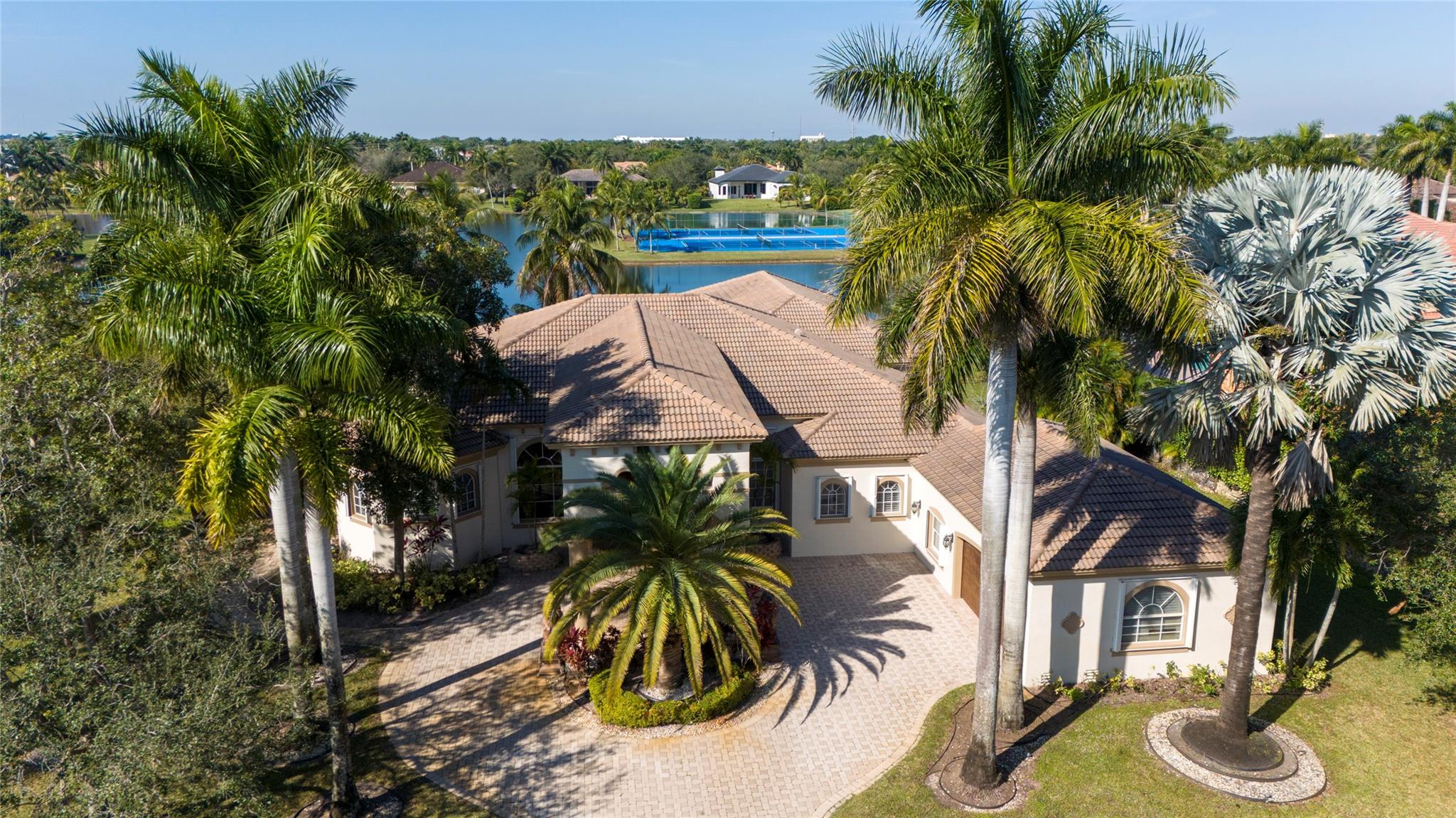 Amazing price on this Exquisite Builder's model Home, with many extras. Imagine you pull up to the double porte cochere, a warm & welcoming foyer with water view, crown molding, Gourmet kitchen with all high-end top appliances & gas range, island with breakfast area over looking the pool and lake, baskeball court, interior features, sophisticated movie theater system is included, sound system throughout, wet bar, office room, tray ceiling, over sized dinning room, custom Plantation shutters. Great Master Suite. Fabulous pool with heated spa. Full Accordion shutters on all windows and doors. Only 42 homes in this private gated community with a close location to Weston. The Home Theater could be a 5th bedroom. 1000 gallon propane tank for stove and pool heater.