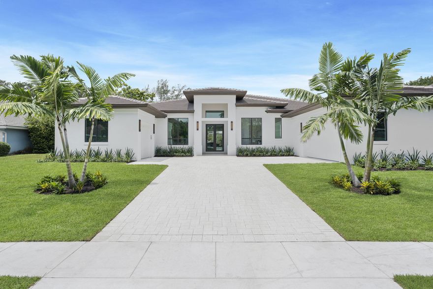 This new construction modern ranch home by Sam Fisch Development features ~6,000 square feet of luxury living on a nearly 1/2 acre lot in the Lands of the President gated community in West Palm Beach. The open-concept great room has soaring 12-foot ceilings and a chef's kitchen with walk-in pantry and spectacular 15-foot island. Seamlessly transition to the covered loggia, summer kitchen, and heated pool/spa, designed for al fresco dining and entertaining against the backdrop of serene lake views. The luxurious primary suite opens up to the outdoor oasis and also includes two expansive walk-in closets, double vanities, and an oversized double shower and freestanding tub. Enjoy waterfront living at its finest in this exclusive gated enclave!