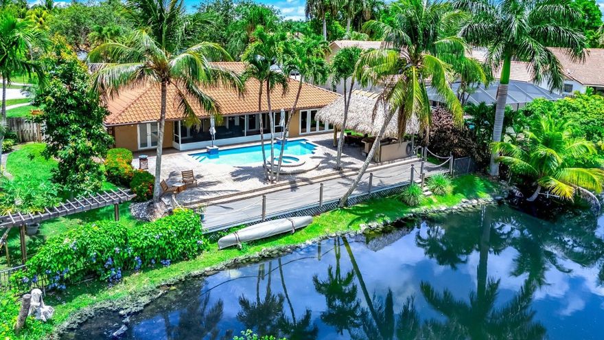 Interior photos coming soon - This 4 bedroom, 3 full bathrooms waterfront Jacaranda Lakes home offers space, style and serenity. Situated on an oversized 112' waterfront lot totaling 12,004 square feet, the backyard retreat features a tiki hut with electric, lighting, refrigerator, grill, tv, fans, pool, and hot tub, all with tranquil water views. Inside, enjoy a stylish bar lounge, dedicated coffee & tea station, all impact windows and doors, 2025 water heater and pool pump, two A/C units, 9 security cameras with NVR, and an S-tile roof. Primary bathroom is a cabana bath, 2 large walk-in closets. Don’t miss this unique blend of comfort and lifestyle in one of Plantation’s most loved neighborhoods. Inquire about extensive additional features list attached