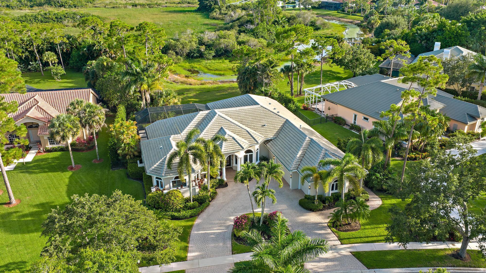 IMMEDIATE PREMIER GOLF MEMBERSHIP AVAILABLE WITH THE PURCHASE OF THIS LUXURY CUSTOM HOME. Expertly renovated and impeccably maintained, this custom estate offers over 3,900 square feet of refined living space designed for effortless comfort and elegant entertaining. Located on a lush, private lot with tranquil preserve views, this residence features a 2023 flat-tile roof and full hurricane protection with accordion shutters--making it truly move-in ready. A circular driveway welcomes you to grand double entry doors, opening to an expansive floor plan rich in architectural detail and upscale transitional finishes. The foyer impresses with soaring coffered ceilings and direct views of the oversized screened-in pool, spa, and serene outdoor living space.