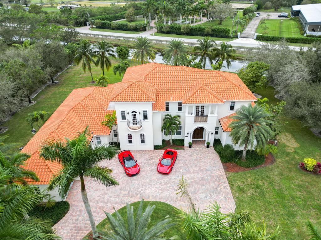 Experience unparalleled luxury in this 6,823-sq-ft under air, gated estate on 1.16 acres in Wellington's prestigious Aero Club private air park community. Boasting 6 bedrooms, 6.1 baths, open plan kitchen with a gym/media room, office, butler's kitchen, and staff/in-law apartment, this clever layout offers privacy and elegance. The main kitchen, with gas range, wine cellar, and a choice several large entertainment spaces, is a chef's dream. Enjoy sunset views from the deep patio and west-facing pool with resurfaced decking. With no neighbors to the north and a pocket park next door, this estate is private and opulent. Many features include 3-car garage, impact glass throughout, keypad entry. Just 1 mile by golf cart to WEF. Aviation perks include 4,000-ft paved runway and tie down.