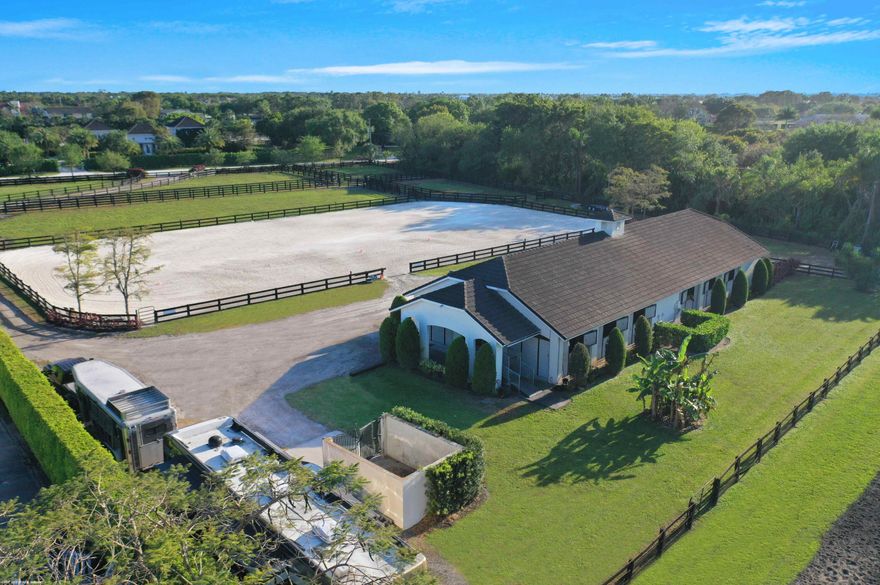 Unique opportunity in Saddle Trail!( Check this property out if you are looking for an equestrian property within hacking distance, that's under 4m and without a large main house!) This private equestrian property is directly located on the maintained bridle path to the show, with a straight forward 1.7 mile hack to Wellington International. The property includes a 13-center aisle barn with mats throughout, fans and water in each stall, tack room, laundry/break room with a half bath, feed room, 2 wash racks, covered front patio with equine Treadmill hookup, 230 x 126 sand arena, 5 large grass paddocks and RV hookup.  Some stalls are leased seasonally.  The rental income is $130,000 for 10 of the 13 stalls for 2025 season.