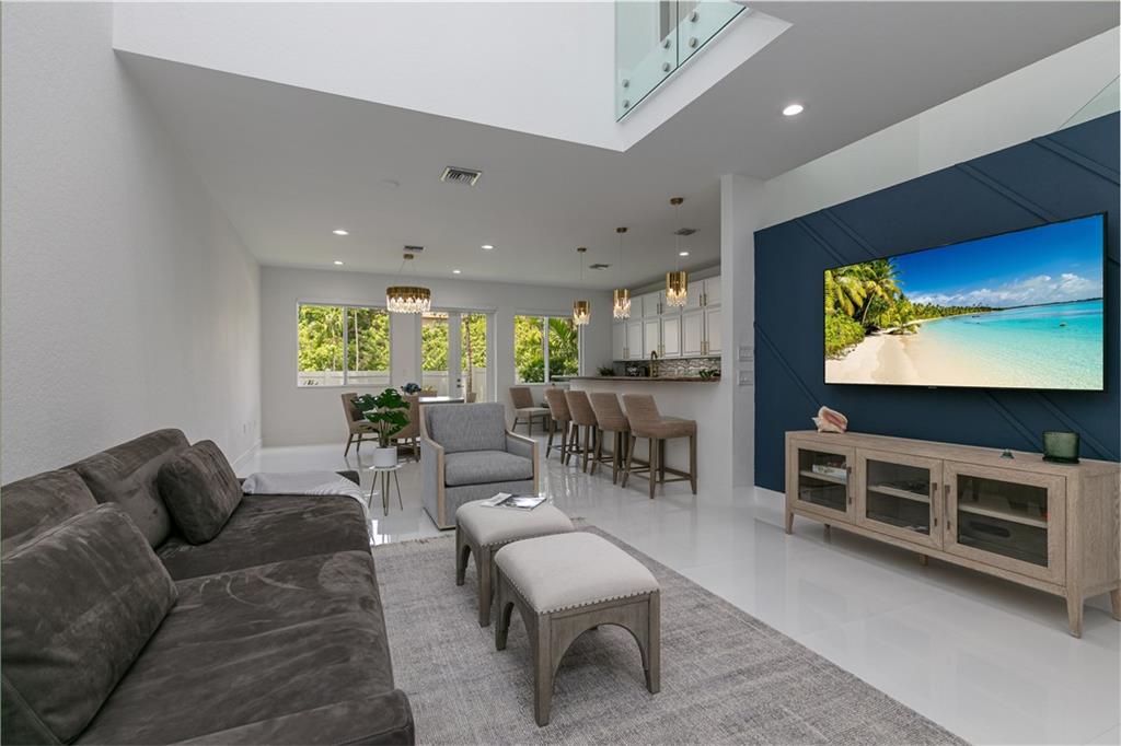 Beautifully, sophisticated 1st & 2nd floor townhome in the heart of happenings in Pompano Beach. Stunning open floor plan, great room with high volume ceilings, large kitchen w/ granite counters, lots of cabinet space, brass accent handles/lighting, SS appl, white porcelain 24x24 tile throughout main floor, high-quality water resistant laminate on the 2nd floor. Stylish modern glass/steel staircase & catwalk railing. Full size washer/dryer, 1 garage, 1 covered carport. Bathrooms are light & bright w/ glossy white vanities, mosaic tile flooring, walk-in shower & soaker tub in the primary bath. Ample closets throughout w/ double walk-in closets in the primary bdrm. Impact windows & doors, small back patio/yard space that's so lovely off the dining & kitchen. Community pool. Gated community.