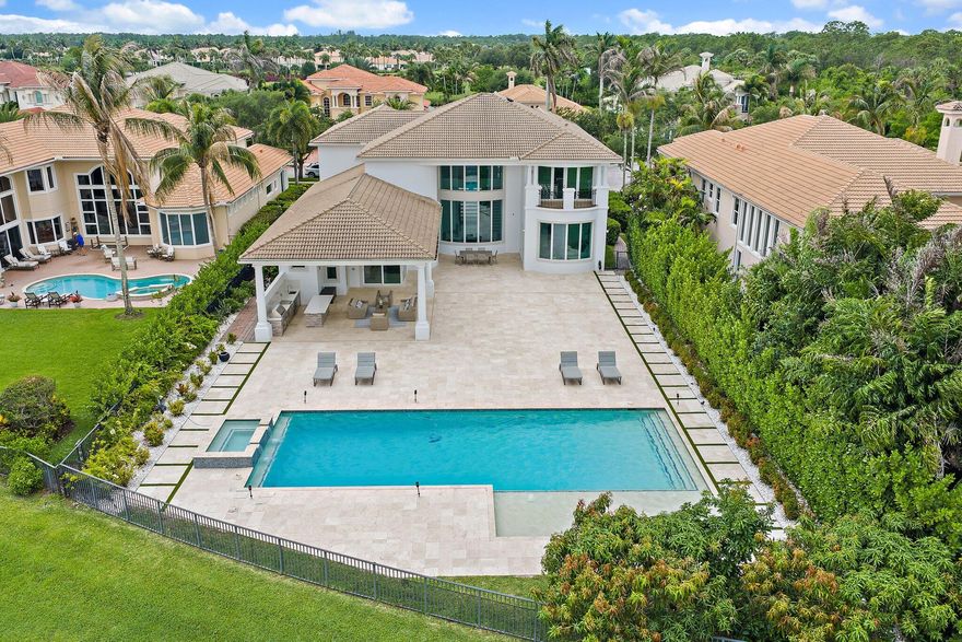 Exquisitely crafted in 2019 and designed to the highest standards, this extraordinary custom residence offers the perfect blend of architectural drama, refined luxury, and effortless indoor outdoor living. From the moment you arrive, the striking high end front door makes a bold statement as it cantilevers open, setting the tone for what lies beyond.  As one of the newer homes in Jupiter Country Club and situated on one of the largest lots in the entire community, this property offers a rare combination of modern construction, expansive outdoor space, and premier positioning that is increasingly difficult to find.  Step inside to a breathtaking grand entry featuring 25 foot coffered ceilings and dramatic walls of glass that flood the home with natural light throughout the day. The expansive floor plan was thoughtfully designed for a large family who loves to entertain, offering generous gathering spaces balanced with private retreats.  The ultra sleek white custom gourmet kitchen is a true showpiece, complete with a waterfall edge center island, porcelain flooring, and seamless flow into the main living and dining areas. The owner's suite is a private sanctuary with floor to ceiling windows, oversized his and hers walk in closets, and a dedicated dressing area. Luxe finishes and elevated design details are showcased in every room.  Freshly painted inside and out, this home has been meticulously cared for and shows like a brand new residence. Every space reflects pride of ownership and thoughtful maintenance.  Outdoors, the property transforms into a private resort. The expansive travertine deck surrounds a stunning 50 by 20 custom pool and spa, complemented by a fully equipped outdoor kitchen, multiple dining and lounging areas, and sweeping long lake views that create the ultimate backdrop for entertaining.  Located within the prestigious gated community of Jupiter Country Club, residents enjoy a lifestyle built around the renowned Greg Norman designed golf course, along with two resort style pools, a state of the art fitness center, lighted tennis courts, and exceptional clubhouse dining.  The location is simply unmatched. Just minutes to the pristine beaches of Jupiter, world class waterfront dining, upscale shopping, and convenient access to I 95 and the Florida Turnpike, this home places you in the heart of everything while still offering privacy and exclusivity.  This is more than a home. It is a statement property designed for those who value quality, space, and a vibrant South Florida lifestyle.