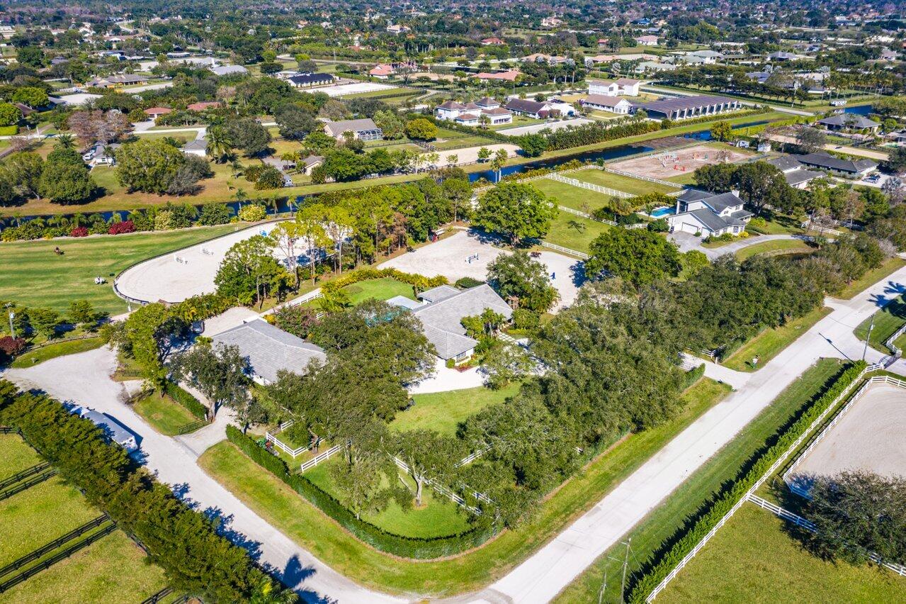 A rare opportunity to own an exceptional equestrian farm on a desirable corner lot, just a short hack to the horse show. This 2.06-acre property features a 6-bedroom pool home and a well-appointed 8-stall barn, built in 2015. Surrounded by mature landscaping and majestic oak trees, it offers natural beauty, shade, and privacy. The barn has its own separate entrance on a quiet cul-de-sac, allowing for discreet access and added separation from the main residence. Designed with both comfort and functionality in mind, this property provides ample space for family, guests, and horses, all in a prime Wellington location just minutes from world-class equestrian venues.