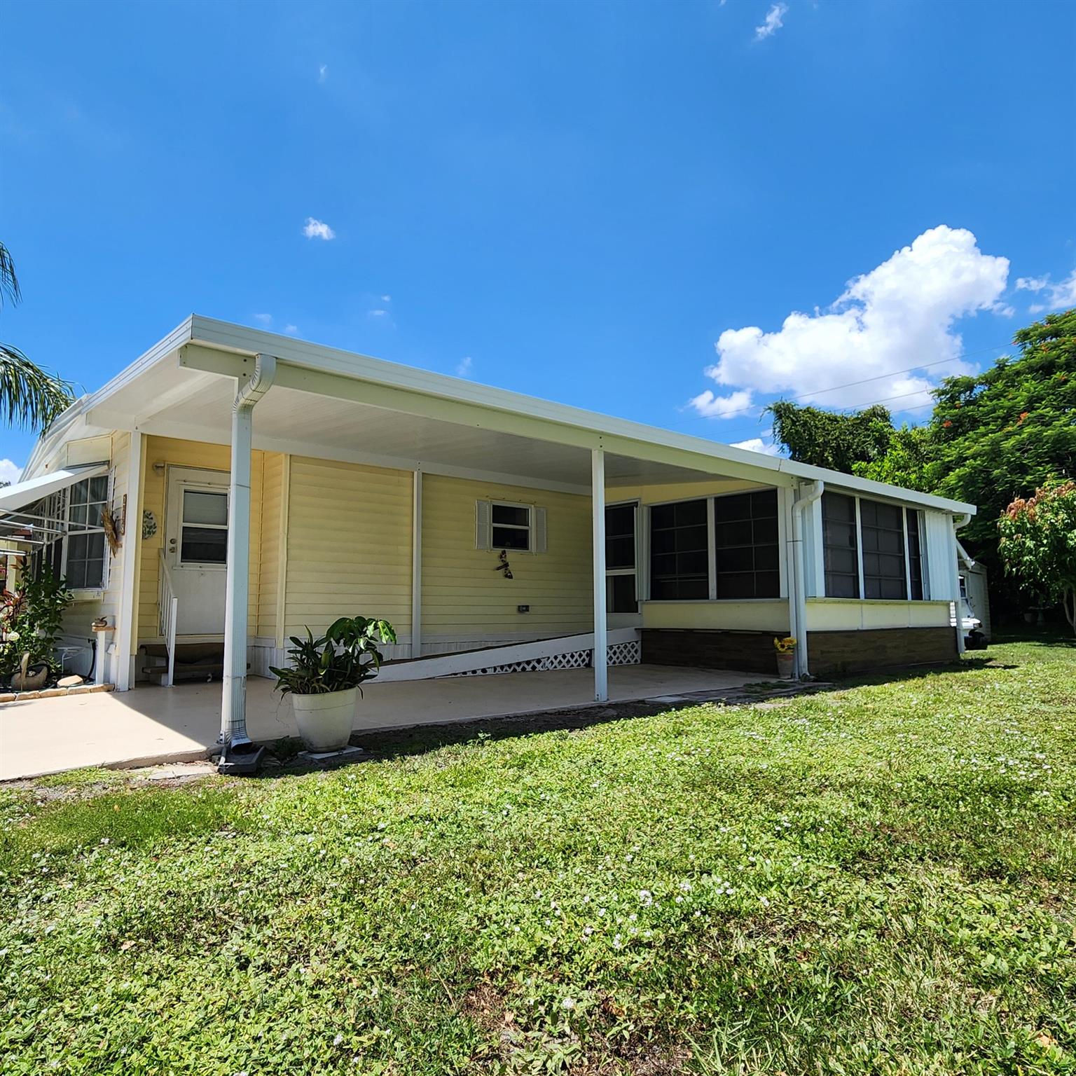 Mini Private Yard! Ideal for a lounge, garden & pets! Furnished, move-in-ready, 2bed/2bath gem is waiting for you! Use the Ramp or Steps to go outside to your private, green oasis; boasting tropical vibes.Inside the charming enclosed Patio/Florida Rm with AC is equipped for an extra room/den/office & more! The master bedroom features an en-suite bathroom & both bedrooms offer generous closet space. You will be pleased w/ this PRIME LOCATION; close to the beach, the mall, grocery stores, diners, coffee shops, post office, banks, pharmacy, hospitals & more. Lot lease of 930.98 includes lawn care, trash, private, free golf course, heated pool, pickleball, tennis, shuffleboard, bocce, gym, library, cards, Mahjong, bible study, wood workshop, dinners, parades, dances & more! AC 2022