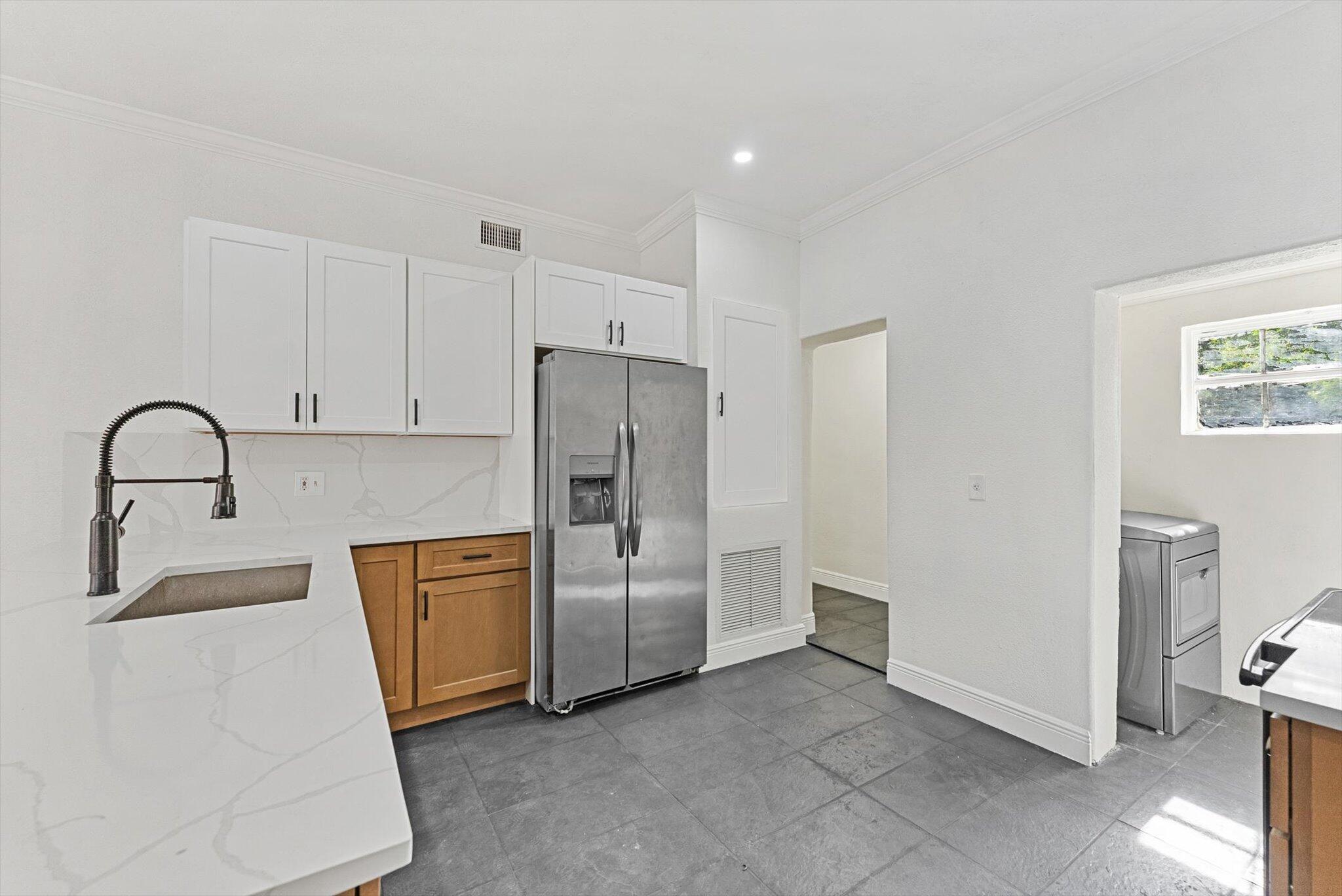 This beautifully renovated Spanish-style home in Lake Worth Beach features three bedrooms and one bathroom. The residence seamlessly blends original charm with modern upgrades, including an arched solid wood front door and a French door leading to the versatile third bedroom or office. The kitchen is equipped with elegant white upper cabinets, wood lower cabinetry, and stunning quartz countertops. A fireplace enhances the living room, while the spacious bedrooms offer ample comfort; the third bedroom is ideal for use as an office. Additional highlights include a large backyard and a detached garage with original barn doors. the Property has Been updated with a new roof and air conditioning system.