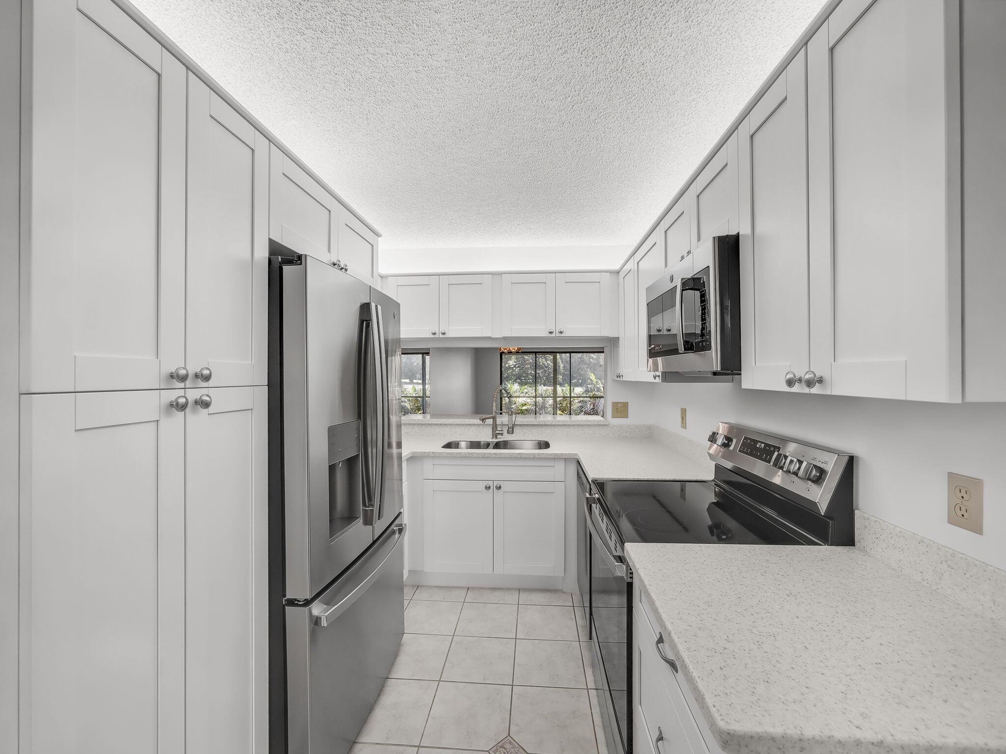 Rarely Available First Floor End Unit with views of the 7th hole fairway and green! This Condo features a Brand New Kitchen with White, Soft Close Shaker Cabinets, Stainless Steel GE Appliances, Quartz Counters and over-cabinet lighting. Other updates include new luxury vinyl plank flooring, new carpet in bedrooms, new modern vanity in the primary bath and extra windows due to the end unit location. There is a large screened patio with a door to access the golf course and a storage room. The building recently had the roof replaced which has been paid for by the current owner. Keystone is a great community with a pool, clubhouse and easy access to the areas best beaches, shopping, dining, A rated schools and the Jupiter Medical Center..