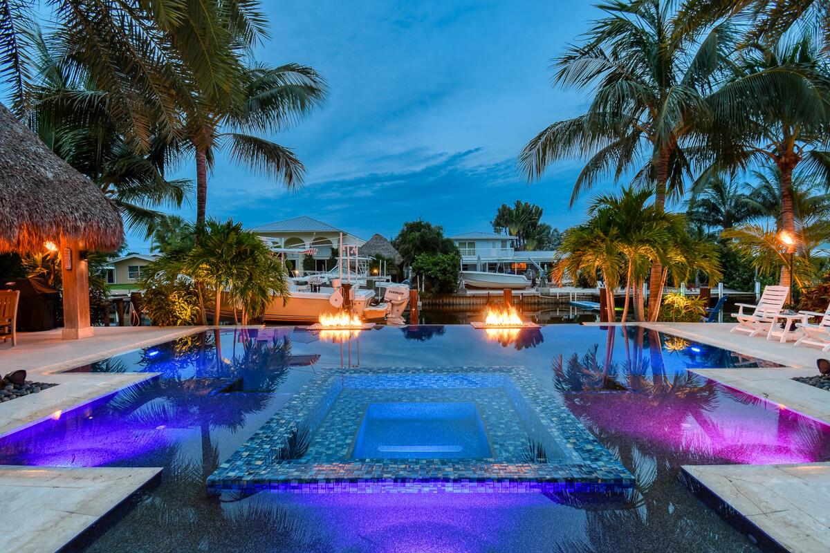 WOW....welcome home!! GORGEOUS WATERFRONT single level 3 bed/3bath updated home with an open floor plan home located on one of the widest canals in the heart of Jupiter. The outdoor space is just spectacular with a custom infinity pool with gas fire feature and euro edge detail. The seawall is 2016, Ipe dock with underwater lighting and 16,000 lb. boat lift included! Putting green, custom cypress louver tiki hut, outdoor shower and gas fire pit incl. gas tiki torches. There is a 500 gallon propane tank that heats pool/spa. Detailed landscape lighting, surround sound throughout ......Your tropical paradise is ready for you!!
