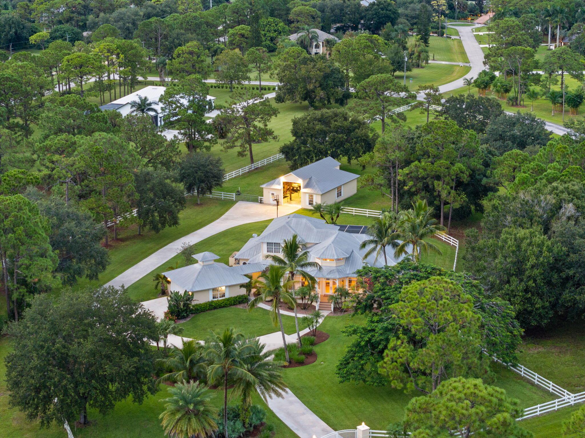 Over 4 acres of dry, fully usable and fenced land in the gated community of Stuart West. This Key West-style estate features a 4-bed, 3-bath pool home with an attached garage, plus a detached 36x46 hurricane-rated RV barn with 12x14 doors and 100-amp service. Inside, enjoy a cozy fireplace, custom finishes, and a wraparound porch. Outside, a beautifully redone pool and over an acre of irrigated landscaping surrounded by mature oaks and vibrant Poincianas. A 400-ft concrete driveway leads to the back acreage, ideal for horses, RVs, or boats. Fully fenced with electric gate, whole-home generator, and no wetlands. A rare mix of privacy, charm, and functionality in one of Martin County's premier acreage communities