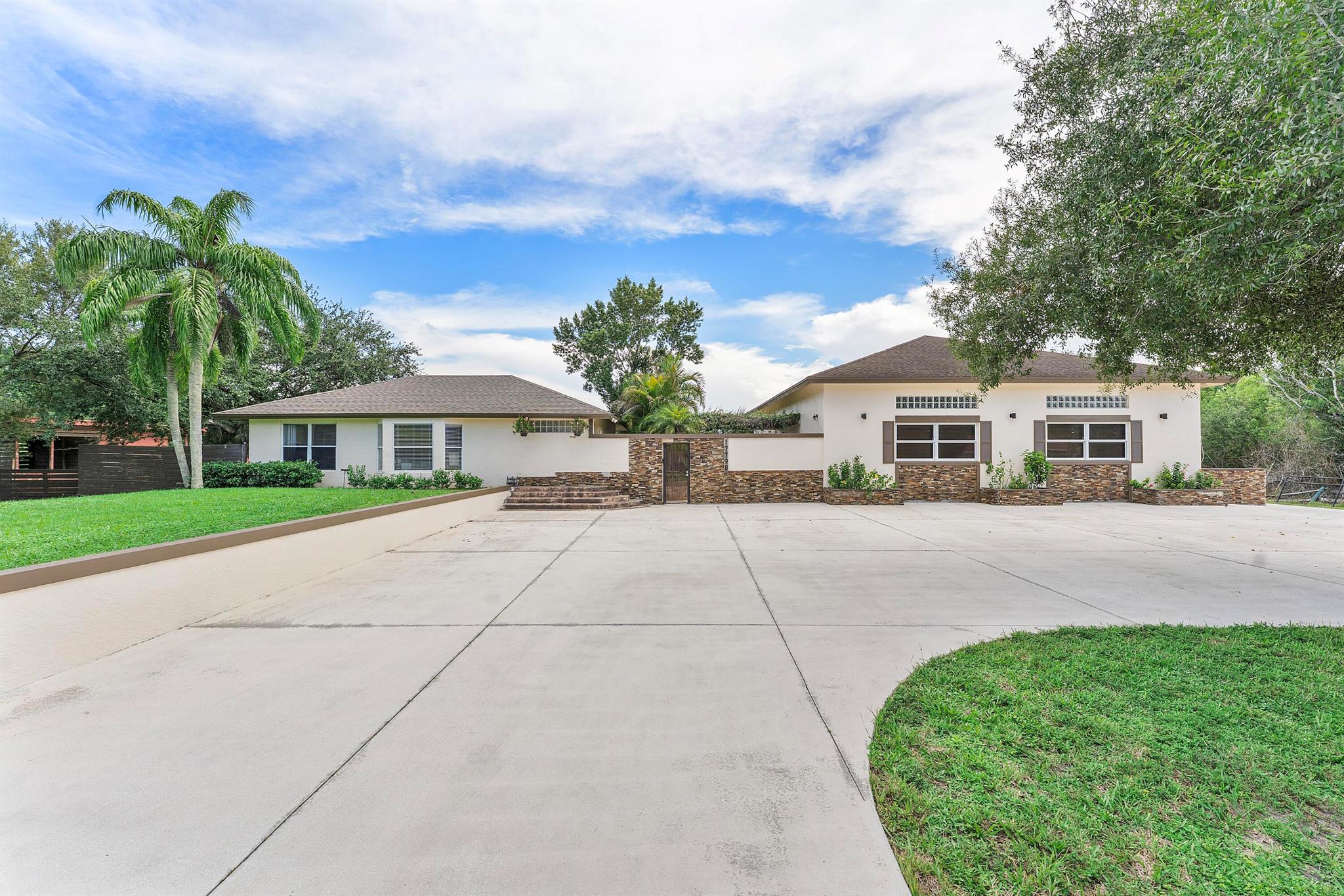 This unique 2 bedroom, 2 bathroom home sits on 1.47 acres in the acreage and comes with a massive 2,000 square foot detatched structure that is air conditioned and packed with all you need for entertainment to include things like, a movie theater, fish tank, a full bar, plus plenty of space to make it your home office or hangout spot. Main home is 809 sq. feet complete with new appliances, partial impact glass, AC is 2020. Outside you'll find a barn, partially fenced, and a pad for your RV or boat.