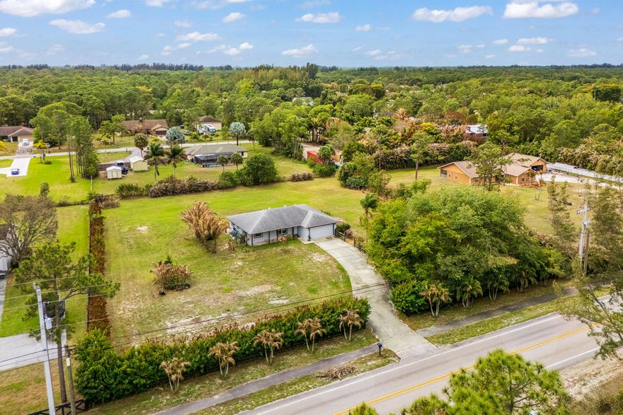 Experience the perfect blend of modern upgrades and peaceful country living in this completely remodeled home located in the highly desirable community of The Acreage. This beautiful property features 3 bedrooms, 2 bathrooms plus a flex room offering living space for an office, gym, or guest area. A spacious kitchen with new stainless steel appliances, quartz countertops, and shaker cabinetry with large island for entertaining. Situated on 1.60 acres on a paved road, the property includes an outdoor pergola, firepit, and playground perfect for entertaining and enjoying the Florida lifestyle with plenty of room for a pool, toys, animals, or expansion.  Don't miss the opportunity to own this move-in ready property and enjoy the freedom of the Acreage with no HOA!!!