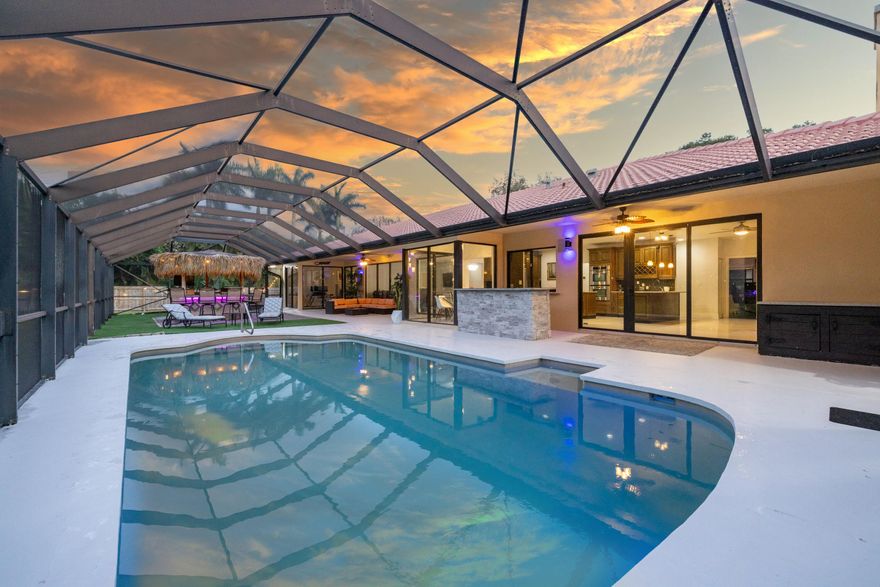 Rare 1.02-Acre Oasis in Boca Raton with Boat & RV Storage! Located in a low-HOA community with A-rated schools, this fully remodeled 4BR+Den/3BA pool home defines Florida luxury. The interior boasts 9' ceilings, wood-look tile, and a split floor plan. The primary suite is a true sanctuary with a spa bath, double waterfall showers, 6 body jets, and a Toto bidet. The gourmet kitchen shines with granite and an oversized island. Head outside to a Custom Tiki bar, summer kitchen, and a screened oversized saltwater pool. Complete with Impact Windows, a Chicago-brick den, and a wood-burning fireplace, this home blends high-tech with timeless character. Experience a private botanical garden on a fully fenced acre lot. The grounds feature over 9 varieties of fruit trees—including Monkey Finger Bananas, Avocado, Jackfruit, Sapodilla, and Brazilian Cherries. The expansive outdoor area is designed for entertaining with custom landscape lighting and a cabana bath. The garage is air-conditioned. The community offers access to a kayaking / fishing pier, park, tennis and basketball courts. Serene acreage living just minutes from major highways, upscale shopping, and dining. This property offers the space of the countryside with the prestige of a Boca address. All measurements are approximate. See the 3D virtual walkthrough.