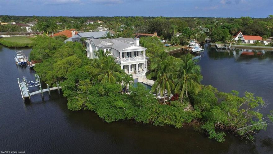 Located on the Loxahatchee River, this 4 bedroom + office/den Key West home is a hidden tropical oasis with panoramic water views every where you turn. A home that is a must see! On its own peninsula with 260 feet of water this luxury home exemplifies top quality and designer touches. Perfection for the person who appreciates living on the River and wants high end. The gourmet kitchen has Thermador appliances, custom made cabinetry and moldings throughout the entire home, hardwood floors, impact windows, wraparound balconies with spectacular views, outdoor covered area, elevator, dock and so much more. This charming home awaits you.  Parcel adjacent is also available with additional 100 ft. of frontage.