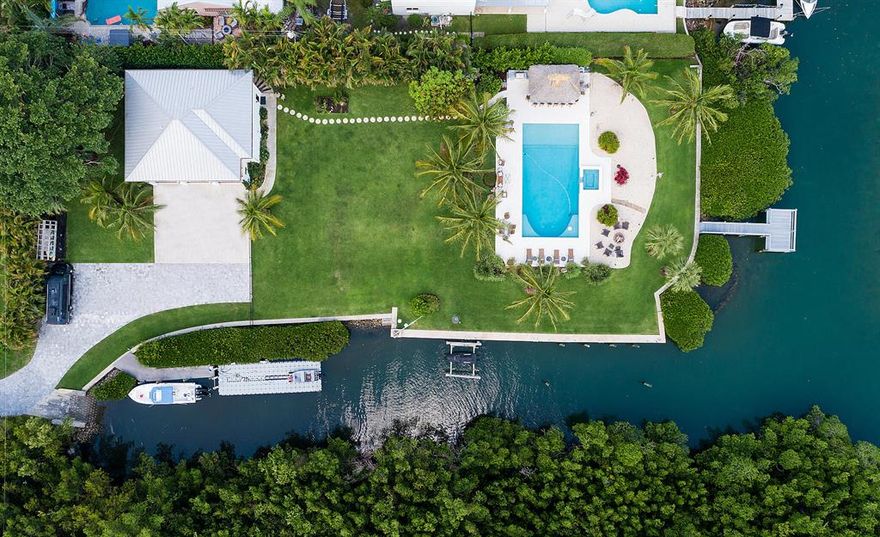 Build your own dream home! This rare waterfront lot, just minutes from the Jupiter inlet, offers expansive blue-water views. This lot, which has 125' of direct river frontage and 225' of canal access, is just under 1 acre. The property includes a 3/2 guest house, private driveway, boat ramp, boat lift, new dock, and newly renovated pool, deck and spa. The high end outdoor kitchen, protected by a tiki hut, includes built-in gas cooktop, grill, smoker and rotisserie, two refrigerators, one beverage refrigerator, double-drawer freezer, ice maker, kegerator, 60-inch flat screen tv and enclosed dry storage. Other features include a fire pit, Sonos surround-sound system for the pool area, gas tiki torches, outdoor shower and Luma outdoor security system. Mature landscaping and mangroves.