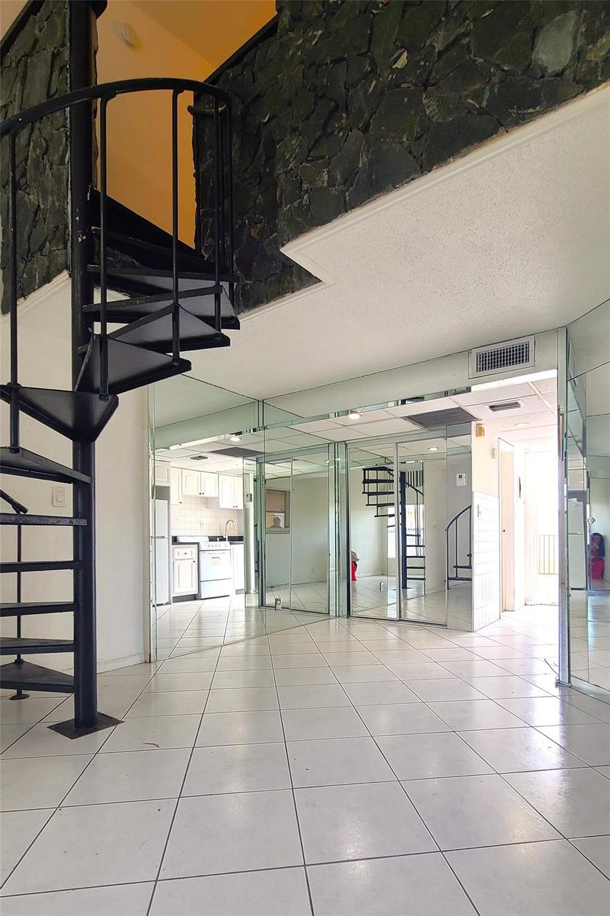 Mid-Century 2 Story Loft Apartment. This unique unit offers 2 levels of living space accessed by a Spiral Metal Staircase. The first level is made for entertaining guests, relaxing or working from home. Mirrored walls not only enhance but visually expand the living space and the raw black granite accent wall adds for a dramatic entrance. Galley kitchen with washer/dryer hookups leads out to an open large semi-private terrace. Upstairs is a private large sleeping room with double closets and private ensuite bathroom. Under covered reserved parking. Close proximity to dining, shopping, entertainment and transportation.