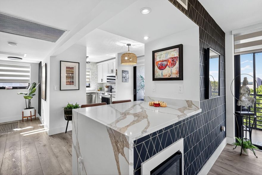 Stunning fully remodeled 2BR/2BA top-floor corner unit, 1,187 sq ft of open-concept living with panoramic garden and lake views, no neighbors above. Designer kitchen, quartz waterfall island, marble backsplash, white cabinetry, and stainless steel appliances. Interior features include luxury vinyl plank flooring throughout, impact windows and sliders, motorized shades, and custom built-in closet systems in both bedrooms. The spa-style primary suite offers barn doors, a dual vanity, mosaic tile finishes, and a spacious walk-in closet. Additional upgrades: New ventless LG washer/dryer, tankless water heater, whole-home water filtration system, and a 2025 A/C air handler and compressor.  2 oversized screened balconies with privacy roll-down shades, plus a same-floor oversized storage unit.