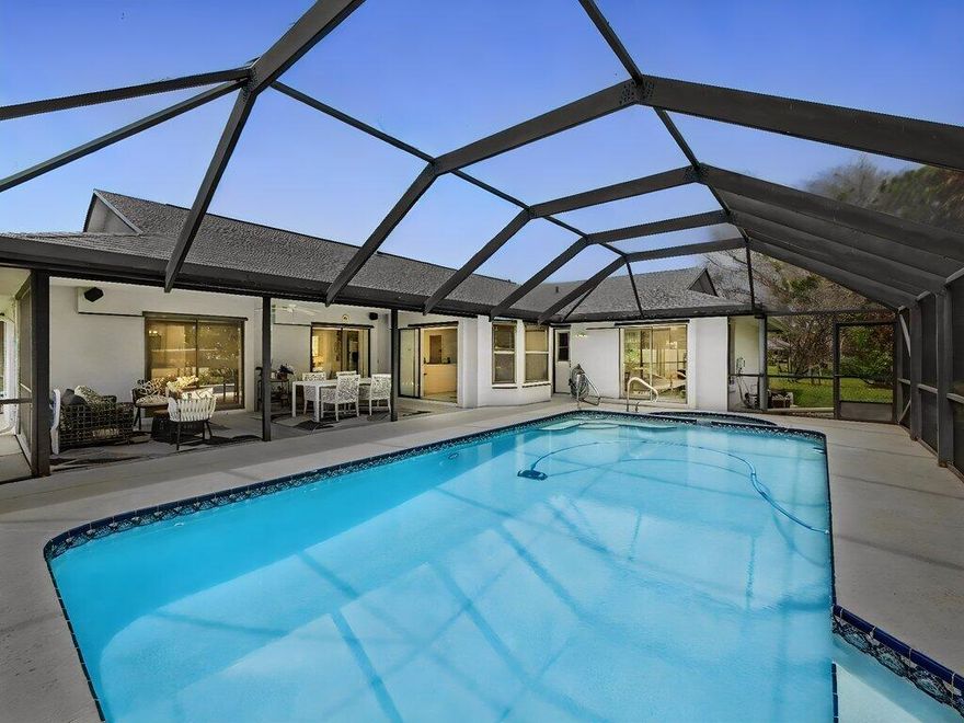 Welcome to this exceptionally maintained property offering space, privacy, and thoughtful updates. With no HOA, located in Sandpiper Bay in Port St. Lucie, this home is situated on an oversized lot. The property is surrounded by mature landscaping and fruit trees, where beautiful wildlife can often be seen, creating a serene and lush environment. Inside, you'll find a desirable open split floor plan with vaulted ceilings that enhance the spacious, airy feel of the home. Featuring three spacious bedrooms and two well-appointed bathrooms, this layout is ideal for both everyday living and entertaining. The two-car garage includes a unique air-conditioned tool room for climate-controlled storage and workspace.  With double glass sliding doors in most rooms that open to the spacious patio/pool, you will feel the natural indoor-outdoor flow.  Step outside to enjoy the expansive oversized patio, perfect for gatherings, overlooking a large sparkling pool and relaxing spa. The backyard is a true highlight—private, green, and peaceful, with no homes or roads behind, offering a rare sense of seclusion. Additional features include a convenient Electrolux central vacuum system and numerous recent upgrades for peace of mind: Roof replaced in 2022, Gutters installed in 2022, Window screens updated in 2023, Pool pump replaced in 2022, Pool screen enclosure replaced in 2019, Main AC replaced in 2026, Tankless water heater replaced in 2021, Range replaced in 2022, Dishwasher replaced in 2023.  Come see this well maintained home that combines comfort, functionality, and privacy—ready for its next owner to make their own.