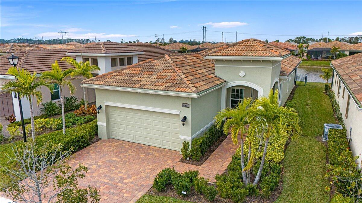 Waterfront 'Casita' Model in Verano PGA Village. Discover lakefront living in this immaculate 2 Bedroom's, 2 Bath's plus large den/office & 2 car garage featuring sleek epoxy flooring. Built with CBS construction, a barrel tile roof, hurricane impact windows and doors, this home offers both durability and style. Details include volume ceilings & tile in main areas. The open kitchen is a chef's dream, showcasing quartz countertops, a glass backsplash, stainless steel appliances (new refrigerator), 42'' soft-close cabinets, a breakfast bar island & pantry. The spacious master suite includes a walk-in closet, dual sinks, and a seamless glass shower, while the split floor plan ensures privacy. Beautiful tranquil lake views includes screen enclosed lanai & spacious fenced backyard.