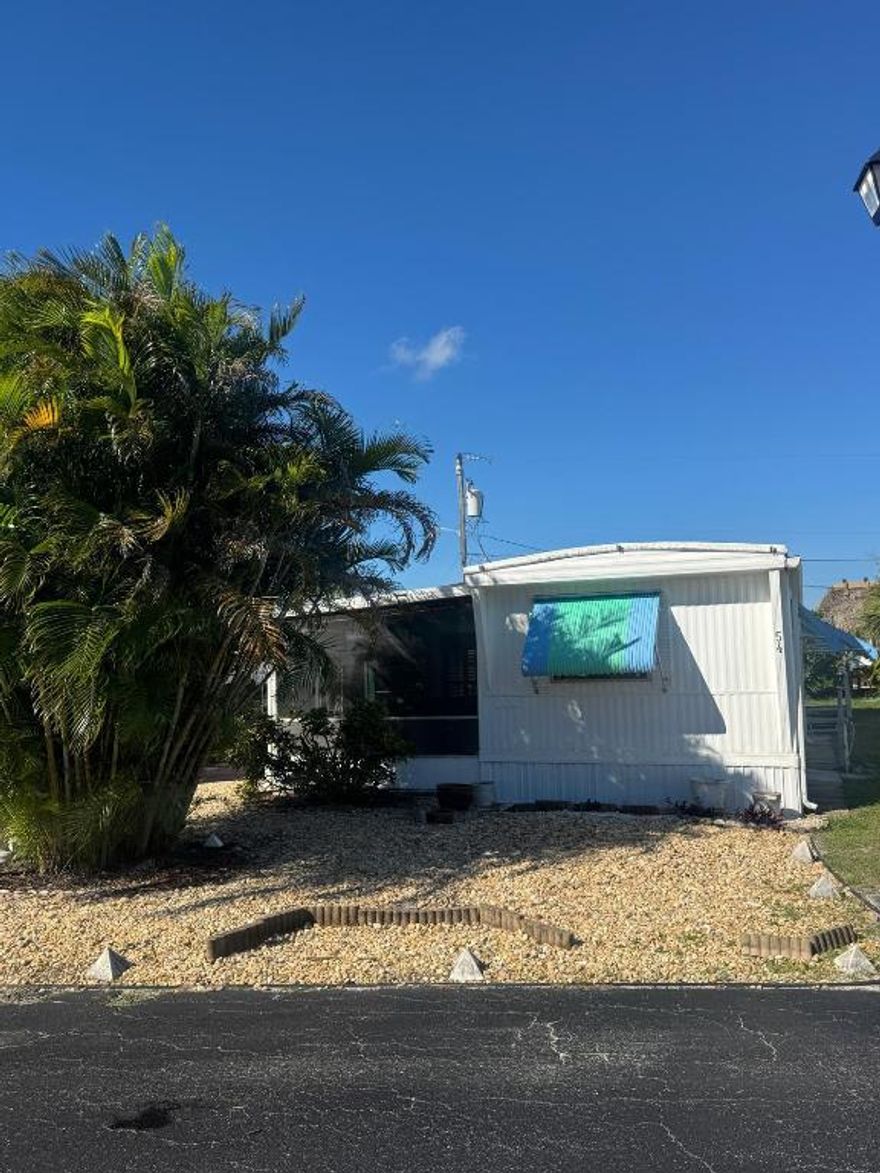 Spacious & well kept, expanded singlewide in Woodbridge Co-Op, 55+ community in Hobe Sound. 35 Year Olds are allowed to live w a 55+ share holder. 2 Bedrm/2 Bath SPLIT PLAN. Aluminum Roof.,, 2016 A/C just serviced w 1 yr warranty still in place. new LG washer 2023, Dryer 2025, New Carport 2014 w decorative floor. This home has so many extras & great curb appeal. LR has windows galore & charm - 1 step up to open kitchen & dining area. Bedrooms off to the left & right. So perfect for visiting friends & family. Woodbridge has a community heated pool, shuffleboard & a host of clubs & activities. The Co-Op monthly fee of $250/mo includes community water/sewer, cable and all the amenities. Minutes to ocean beaches, shopping, restaurants & entertainment. You own the land as a part of the CO-OP