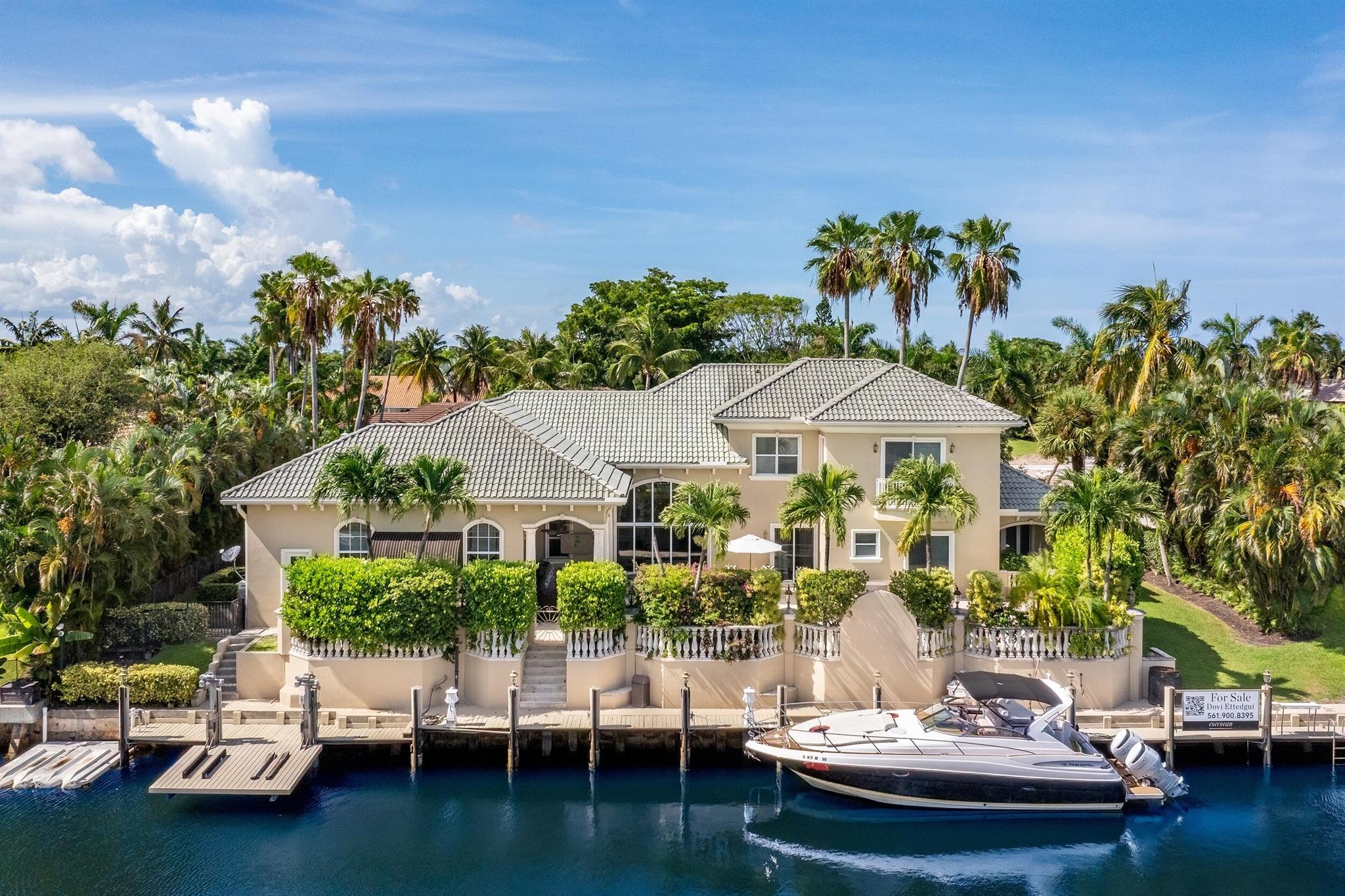 Tucked within the prestigious enclave of Boca Bay Colony, this waterfront estate blends timeless elegance with resort-style living. Set on over one-third of an acre with 150 feet of deep-water frontage, this five-bedroom, six-and-a-half-bath residence is designed for the ultimate South Florida lifestyle, complete with multiple boat accommodations, two floating jet ski docks, and a wide canal offering seamless ocean access.Inside, polished Saturnia marble flooring, high ceilings, and expansive windows fill the home with natural light. The open-concept layout flows effortlessly into the tropically landscaped backyard, where an elevated dock, authentic reclaimed coral decking, and a protected pool area create a private marine sanctuary perfect for entertaining or relaxing year-round.