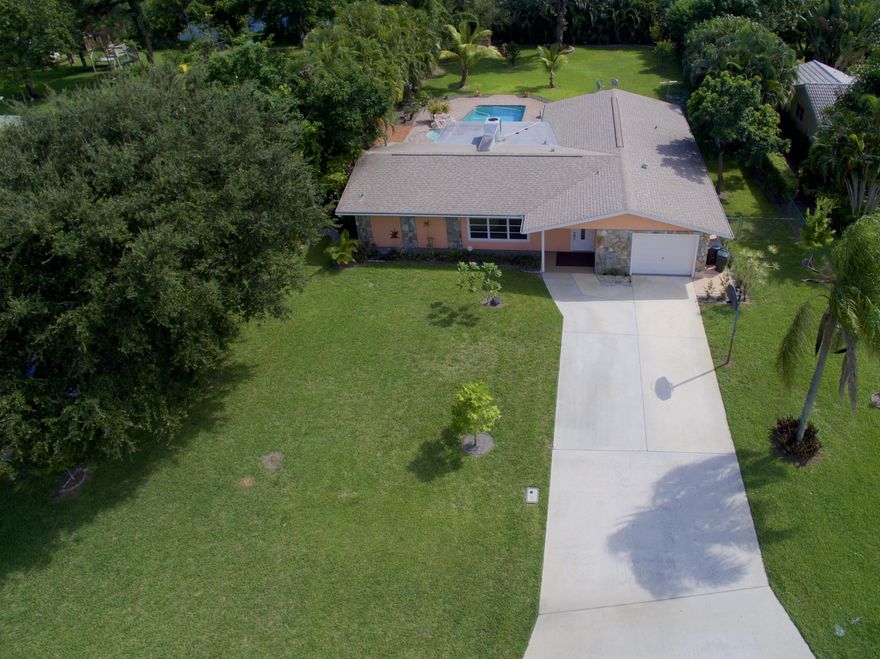 Centrally located in PBG, this super private split bedroom pool home with oversized fenced yard has it all. Extra clean and freshly painted, upgraded granite kitchen with stainless appliances, renovated bathrooms with jacuzzi tub, tile flooring throughout, large walk-in closets in every bedroom, French doors opening to the patio, ceiling fans in every room, crown molding in living area, 2 inch wood blinds throughout and more. The huge backyard is lined with trees for privacy and offers a large pool with 2 water features, expansive partially covered paver patio, boat parking for a large vessel with double gate and a tool shed. Professional landscaping, pool service and pest control are INCLUDED in the rent.