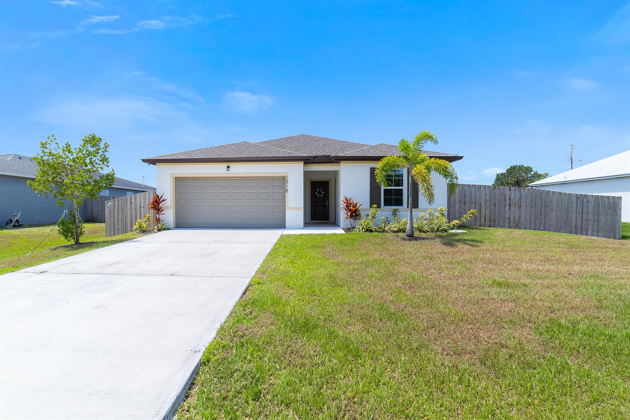 Welcome home to this immaculate 4 bedroom 3 bath opportunity located in the highly sought after NO HOA area of central Port St. Lucie. As soon as you enter, you immediately notice the abundant natural light and welcoming finishes of this 2023 build. This unique property boasts an entire, private guest wing that is accessible from inside, but which also has its own separate entrance. This feature provides its own bedroom, full bath and living space which includes granite countertop space, cabinetry and a sink. This suite offers great flexibility as a guest suite, additional bedroom or an office area. Tile flooring throughout provides great continuity and easy maintenance. The large kitchen features stainless steel appliances, modern white cabinetry and large center island with bar