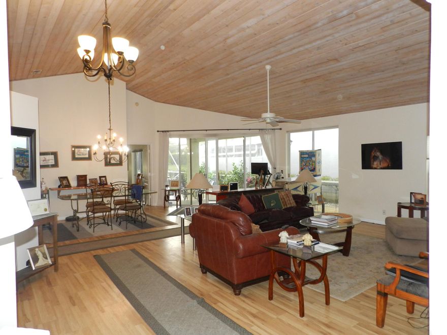 SPACIOUS 2 BEDROOM PLUS DEN/OFFICE GREAT FLOOR PLAN AS YOU ENTER LOOK UP AT THE GORGEOUS TOUNGE AND GROVE WOOD CEILING LIVING ROOM DINNING, AND KITCHEN, CUSTOM CLOSETS THROUGHOUT THE HOME ALSO WOOD ENGINEER FLOORS NEW FLOOR JUST INSTALLED IN THE KITCHEN. THIS BEAUTIFUL HOUSE IS WIRED FOR MUSIC EVEN THE LARGE SCREENED PATIO, WHICH OVERLOOKS A LAKE PLUS IT HAS A BURGULAR ALARM. AS YOUR ENJOYING THE PATIO IT HAS A  BLUE ELECTRONIC AWING FOR COMFORT AND SHADE The Spectacular Entrance LUSH LANDSCAPE GARDEN WINDOW AS YOU ENTER THIS SPACIOUS  HOME YOU WILL SEE THE BEAUTIFUL WOOD CEILING  PRIMARY SUITE IS OFF THF THE LIVING ROOM  WHITE BATHROOM SOAKER TUB DUAL VANITIES GORGEOUS CUSTOM CLOSET PRIVATE WATER CLOSET BEDROOM HAS 2 WINDOWS OVERLOOKS THE LAKE AND A SLIDER DOOR  TO GO TO HUGE SCREEN PATIO WHITE KITCHEN CABINET GRANITE COUNTERTOP.  DEN HAS CUSTOM WALL UNIT   2ND BEDROOM HAS CUSTOM CLOSET  IN THE HALLWAY THERE IS ANOTHER CUSTOM DESIGN CLOSET A WOMENS DREAM.  2 CAR GARAGE IS WERE LAUNDRY ROOM IS. THERE IS A DOOR TO GO OUT TO THE PATIO THE PATIO IS PARADISE OVERLOOKS LAKE L SHAPE SCREENED PATIO  IT HAS A GRILL AREA WITH A BEAUTIFUL BLUE ELECTRICAL  AWNING.  A PARTIAL COVERED PATIO IN CASE OF RAIN ELECTIC OUTSIDE