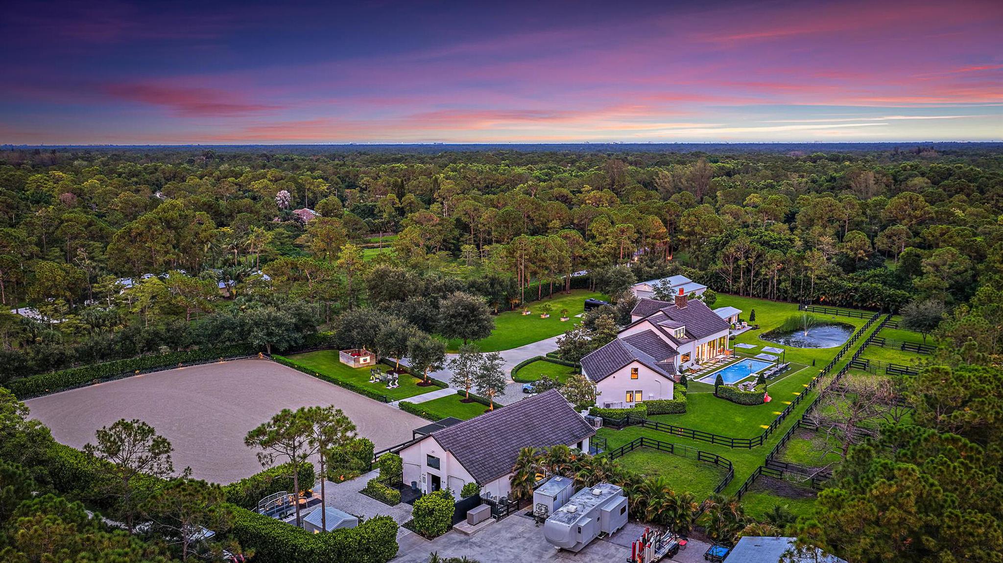 This completely reimagined estate combines timeless charm with modern luxury on 5 private acres in Palm Beach Gardens' coveted equestrian community of Caloosa. Designed as a full retreat, it offers open, sun-filled living spaces and resort-quality amenities inside and out.Walls of windows frame the flowing layout, connecting the designer kitchen, dining area, and inviting living spaces. The primary suite features a morning bar, custom wardrobe closets, and a spa-style bath. Multiple guest suites and a luxury in-home cinema provide space for everyone to unwind.A fully automated Control4 smart home system with Josh AI manages lighting, climate, entertainment, and security--delivering convenience to match the estate's beauty.The backyard is an entertainer's dream with a lap pool