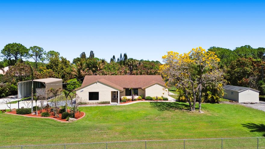Your Private Florida Paradise Awaits Welcome to a rare gem nestled in the heart of The Acreage — where space, privacy, and the Florida lifestyle come together on your own piece of paradise. Tucked away on a lush, fully fenced 1.15 lot with impressive electric iron entry gates, this meticulously upgraded home is the sanctuary your family has been searching for. Inside, No Detail Was Overlooked. The kitchen is well maintained and move-in ready, featuring solid wood cabinets, granite countertops, and stainless steel appliances — including a brand-new refrigerator. Ceramic tile flooring flows throughout the entire home. Every light, ceiling fan, outlet, and switch has been replaced. Crown molding adds a refined, elegant touch throughout, and both the master bathroom and cabana bathroom have been beautifully renovated. Freshly painted inside and out, this home shows like new. Pull up the driveway, take in the lush tropical landscaping and decorative curbing, and you'll already know — this one is different. Flexible Living Space to Grow Into. The garage has been thoughtfully converted into an air-conditioned bonus room complete with its own closet — a generous 420 square feet of flexible space perfect for a home office, playroom, gym, media room, or guest suite. This is the kind of versatile space that modern families truly appreciate and rarely find. Peace of Mind, Built In. Major systems have all been thoughtfully upgraded — a high-efficiency air conditioning system, a whole-home water softener and filtration system, and a new water heater, all backed by warranties. The terrace ceilings and soffits were completely redone with wire rope and cement, ensuring durability and a polished, lasting finish. Impact-resistant doors and windows throughout the home provide security and storm protection, while a smart home security system with cameras covering every area of the property gives your family confidence around the clock. New gutters round out a home that has truly been maintained and improved with care. A Backyard Built for Living. The screened-in pool with a large covered patio is the heart of this outdoor oasis — perfect for entertaining, weekend family fun, or simply unwinding in your own private retreat. An outdoor kitchen means alfresco dining is always on the menu. The lush, manicured grounds are fed by a full irrigation system with a deep well, keeping everything green year-round. An abundance of tropical fruit trees — mango, avocado, plum, cherimoya, loquat, sour orange, and exotic palms — create a truly one-of-a-kind backyard experience. And for those with a boat, RV, or extra vehicles, a large detached covered storage structure provides the space and protection you need — a feature rarely found in any listing. Location That Makes Life Easy. Situated in The Acreage, one of Palm Beach County's most beloved communities known for its spacious lots and relaxed, private lifestyle, you're still remarkably close to everything your family needs. Publix, Trader Joe's, and everyday shopping are just minutes away. The Acreage Community Park — a beloved family hub with athletic fields, playgrounds, and picnic pavilions — is nearby, as is the expansive Okeeheelee Park and Lion Country Safari for weekend adventures the whole family will love. And with the road scheduled to be paved in 2027, the neighborhood is only going to get better — making now the perfect time to plant your roots here. This is more than a home — it's a lifestyle. Properties with this level of care, privacy, and outdoor living rarely come to market. Don't miss your chance to make it yours.